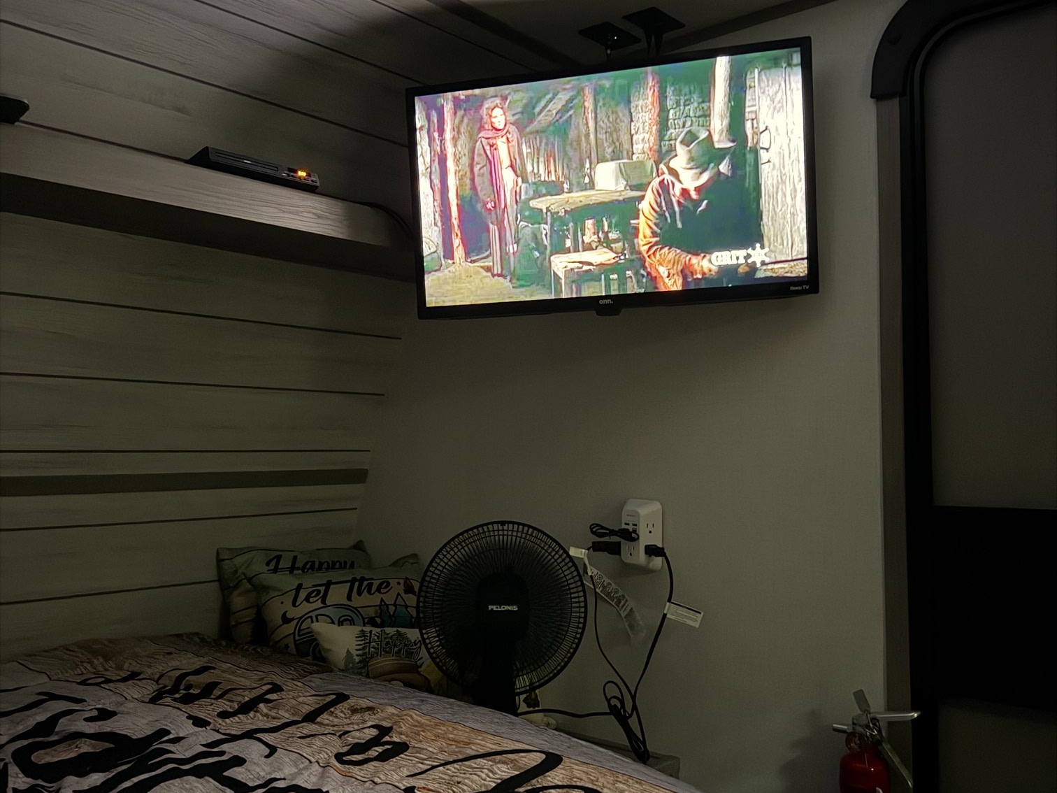 Relax in this cozy RV rental bedroom! Features a wall-mounted TV, a fan for comfort, and a patterned bed with pillows.. Dutchmen Coleman 2024