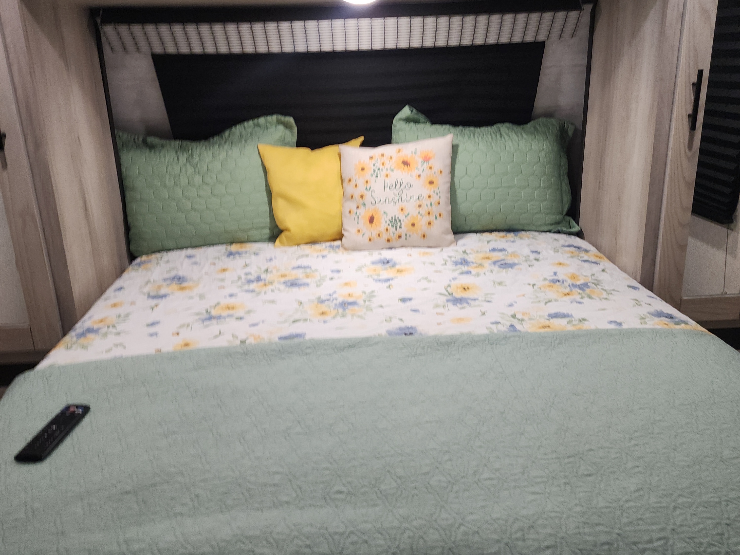 Cozy RV rental bedroom with floral bedding, green & yellow pillows, and a "Hello Sunshine" pillow.. Connect C-281BHSE 2022