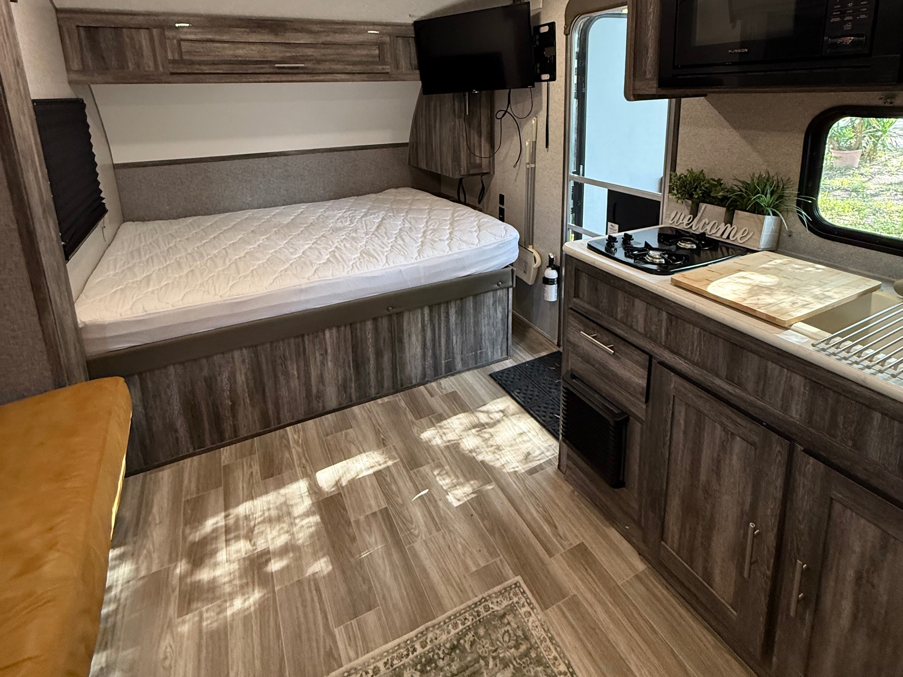 Explore a well-equipped RV rental! This cozy interior features a comfortable bed, compact kitchen, and inviting living space.. Forest River Wildwood FSX 2019