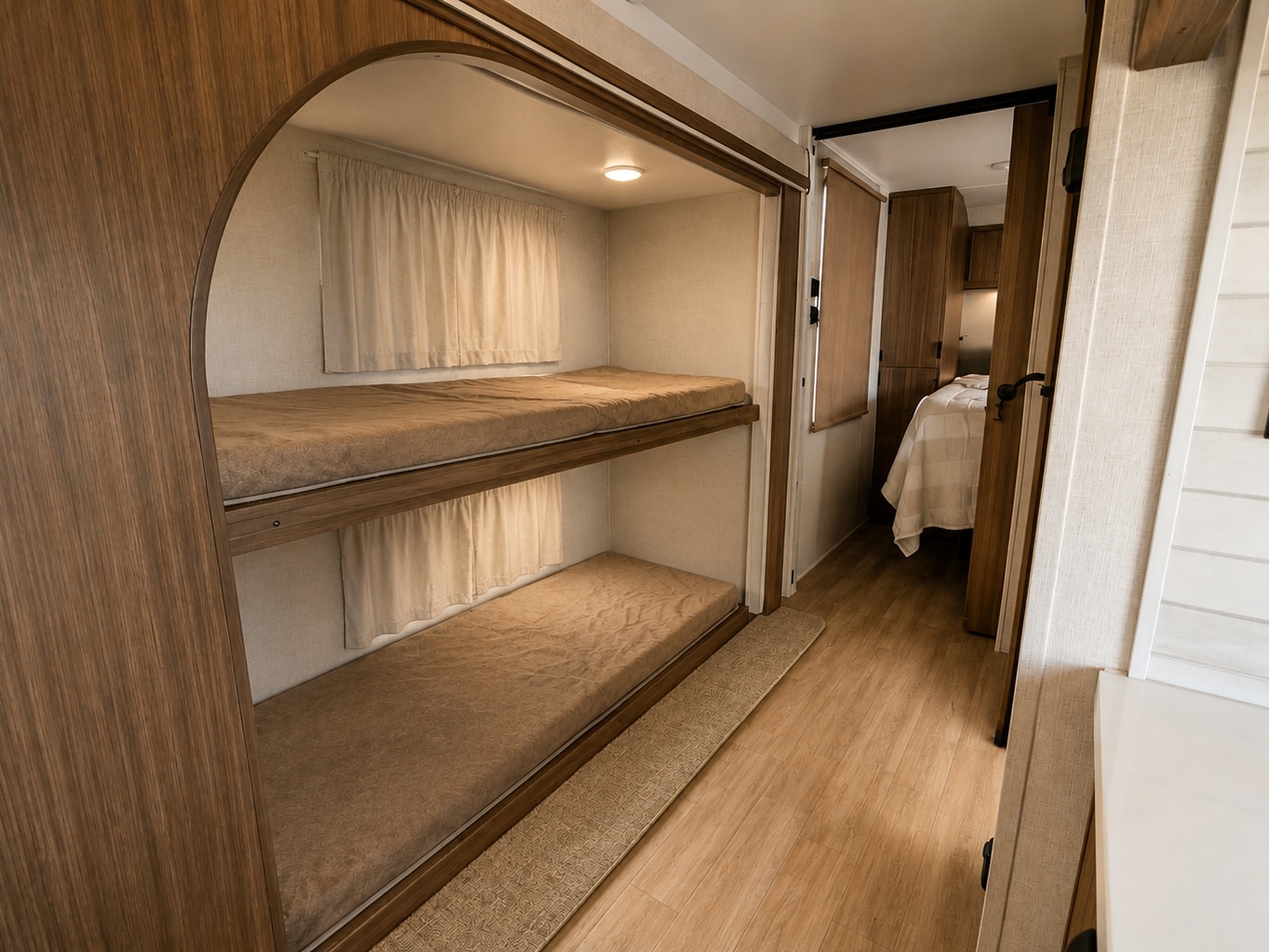Explore this RV rental's cozy bunk beds, complete with soft mattresses & private curtains, leading to a main bedroom.. Forest River Wildwood 2025
