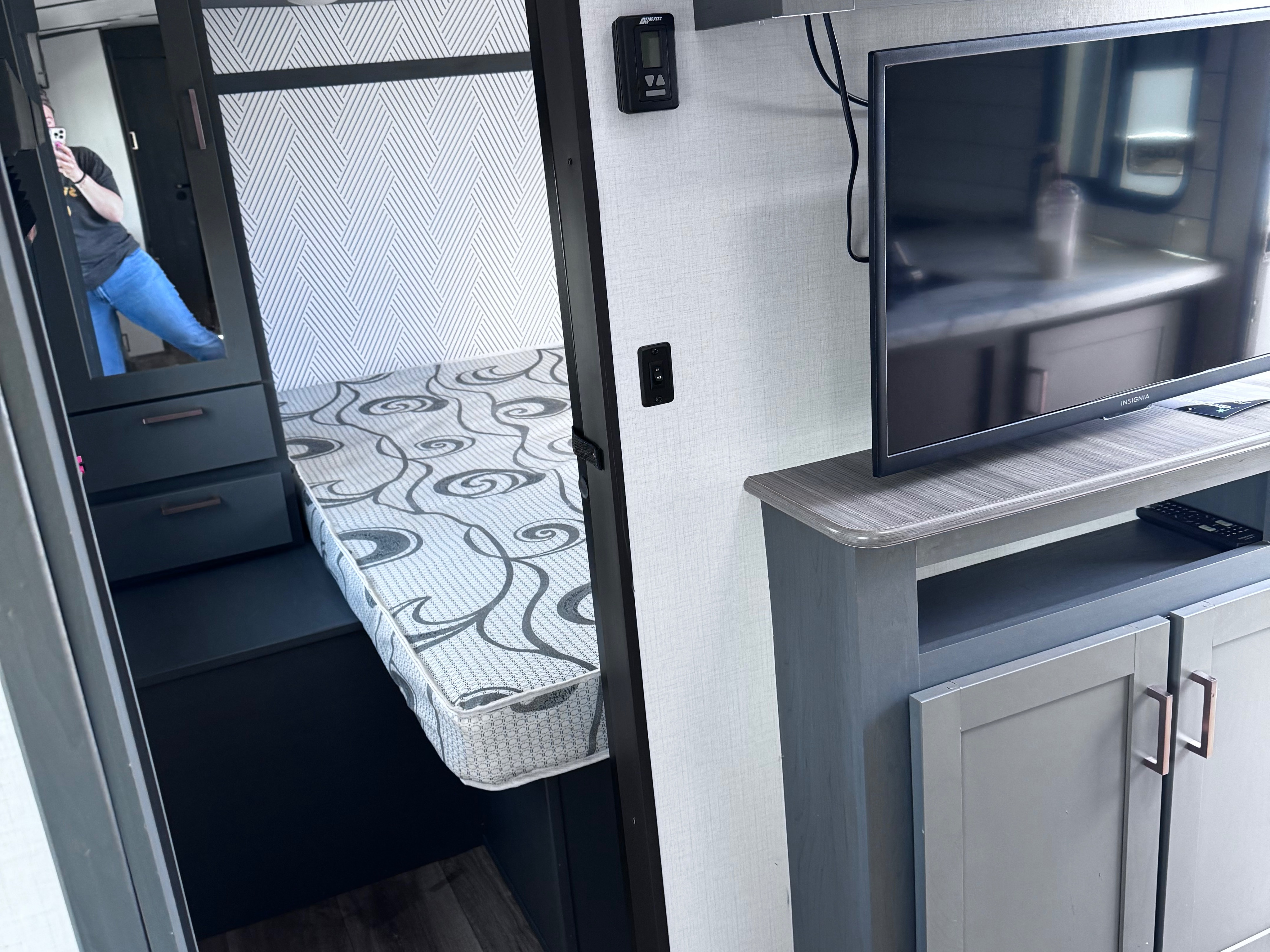 Modern RV rental interior with compact bunk bed area, wall-mounted TV, and storage cabinets in a sleek design.. Keystone RV Bullet Ultra Lite 2022