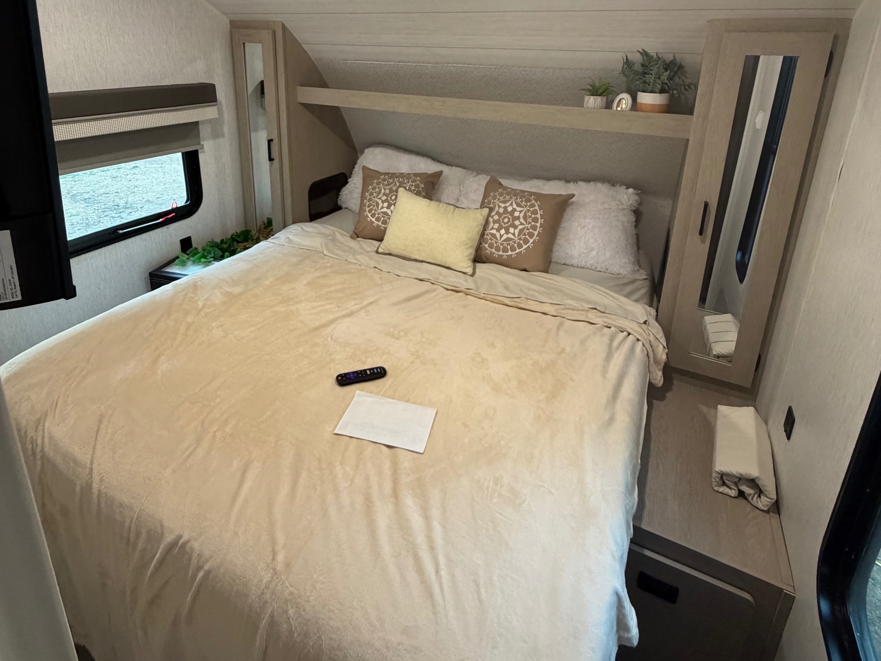 Serene RV rental bedroom featuring a bed with plush pillows, a window, TV, and modern storage. Soft lighting enhances comfort.. Forest River Salem Cruise Lite Platinum 2023