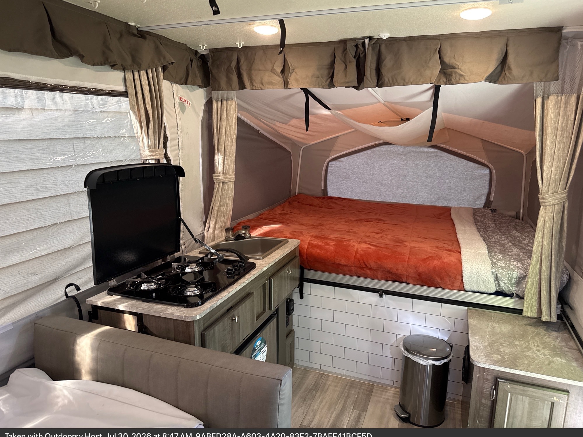 Cozy rv rental pop-up camper interior with bed, kitchen (stove/sink), and seating area.. Forest River Rockwood ESP 2022