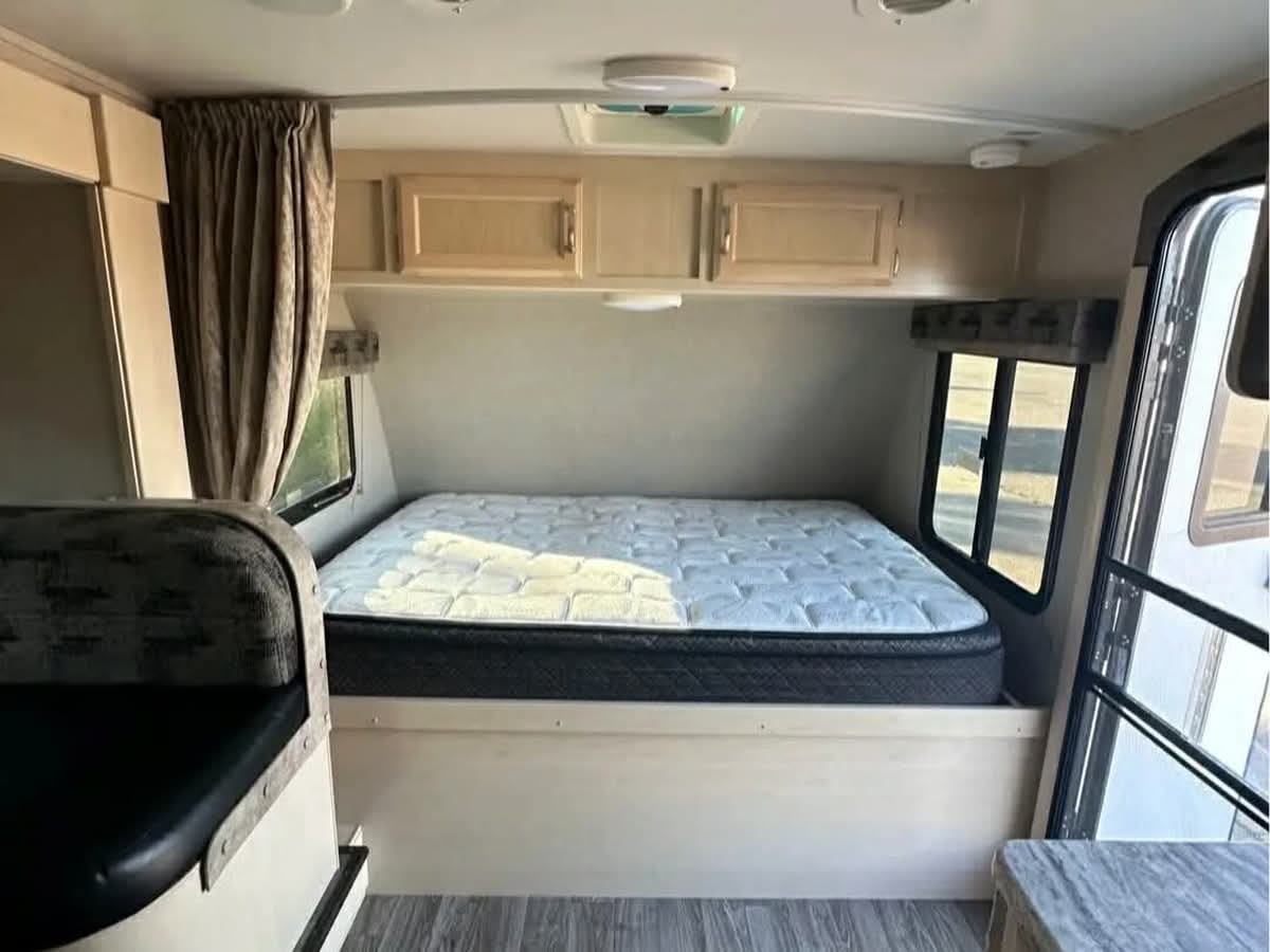 This rv rental offers a bright, compact interior with a comfy bed, overhead cabinets, and a partial view of dinette seating.. Winnebago 2100bh 2019