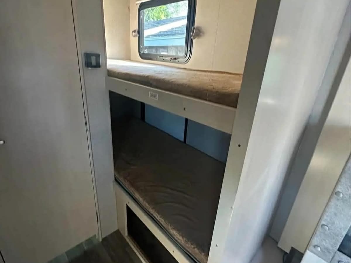 Inside an rv rental, functional bunk beds with mattresses and a window offer compact sleeping for travel.. Winnebago 2100bh 2019