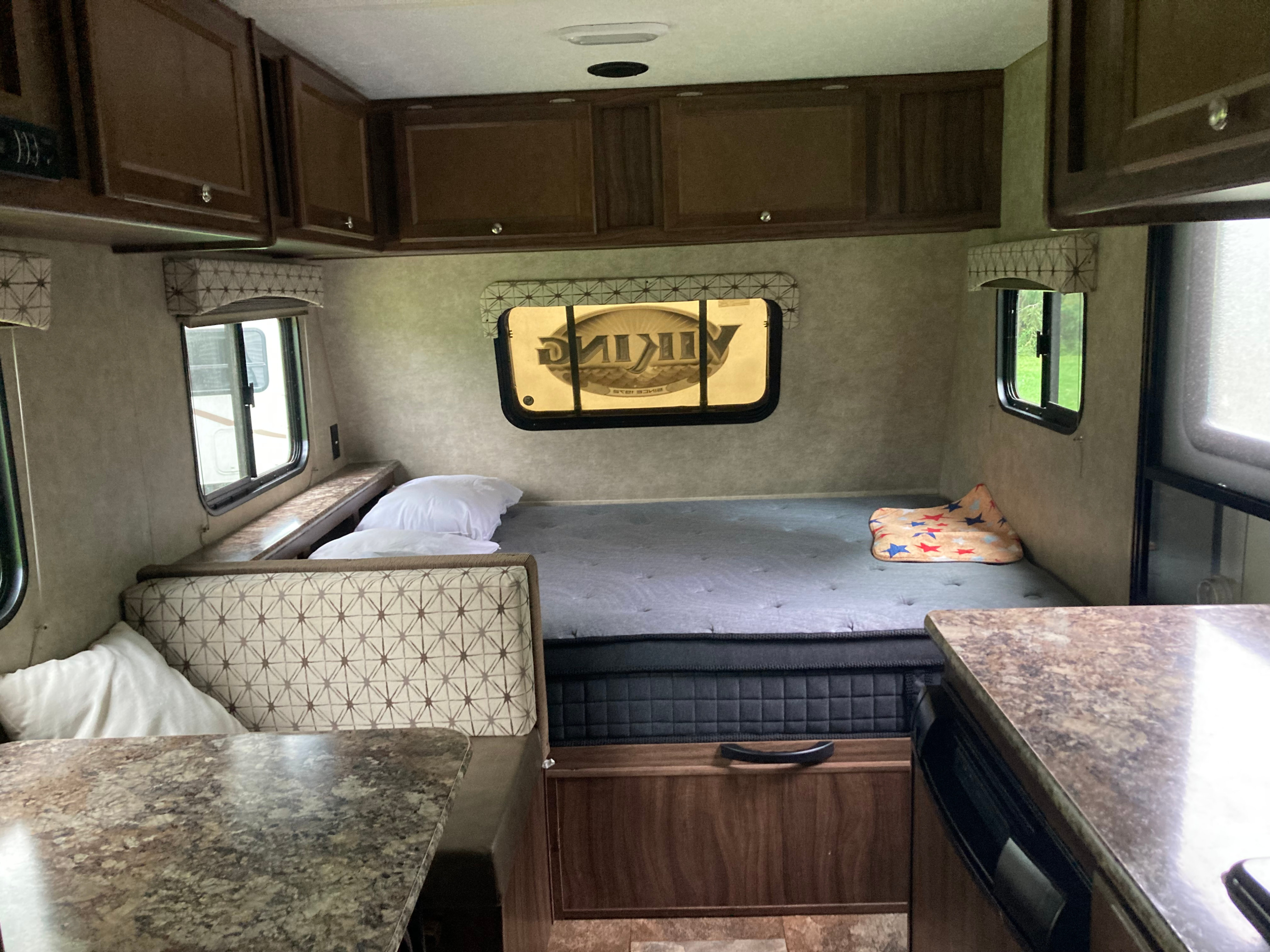 Cozy RV rental interior with a comfortable bed, dinette seating, and overhead storage cabinets in this camper.. Forest River Viking 2017