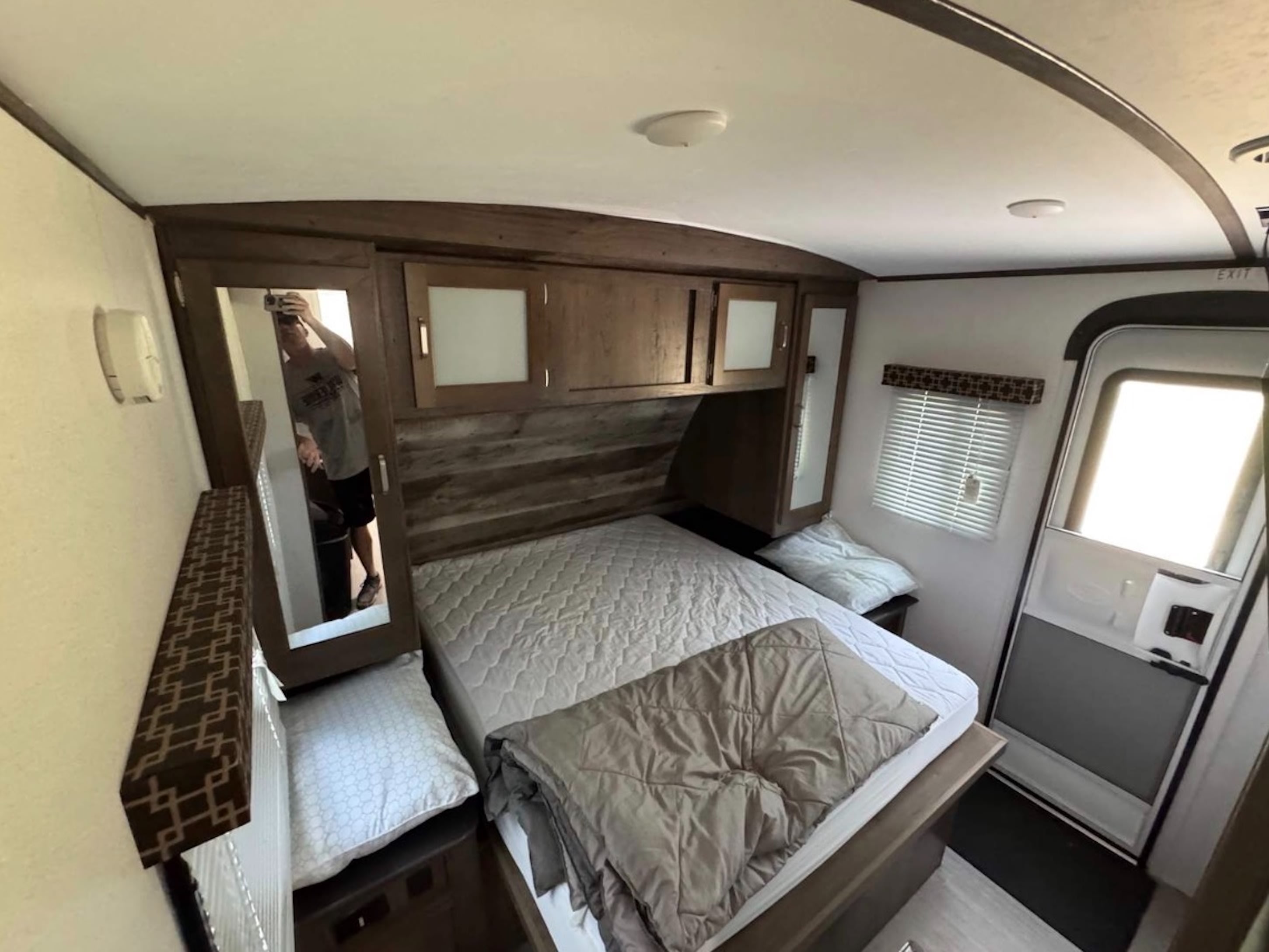 Explore this RV rental bedroom's interior: comfy bed, storage cabinets, and mirror. Ideal for your next camper trip.. Keystone RV Passport Grand Touring 2019