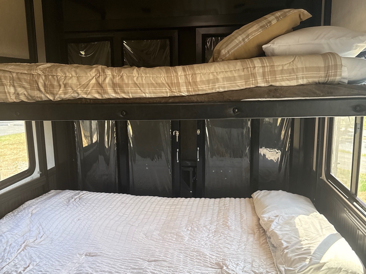 Cozy RV rental bunk bed area with plaid upper bedding and a white lower bed, ready for travelers.. Heartland Cyclone 2018