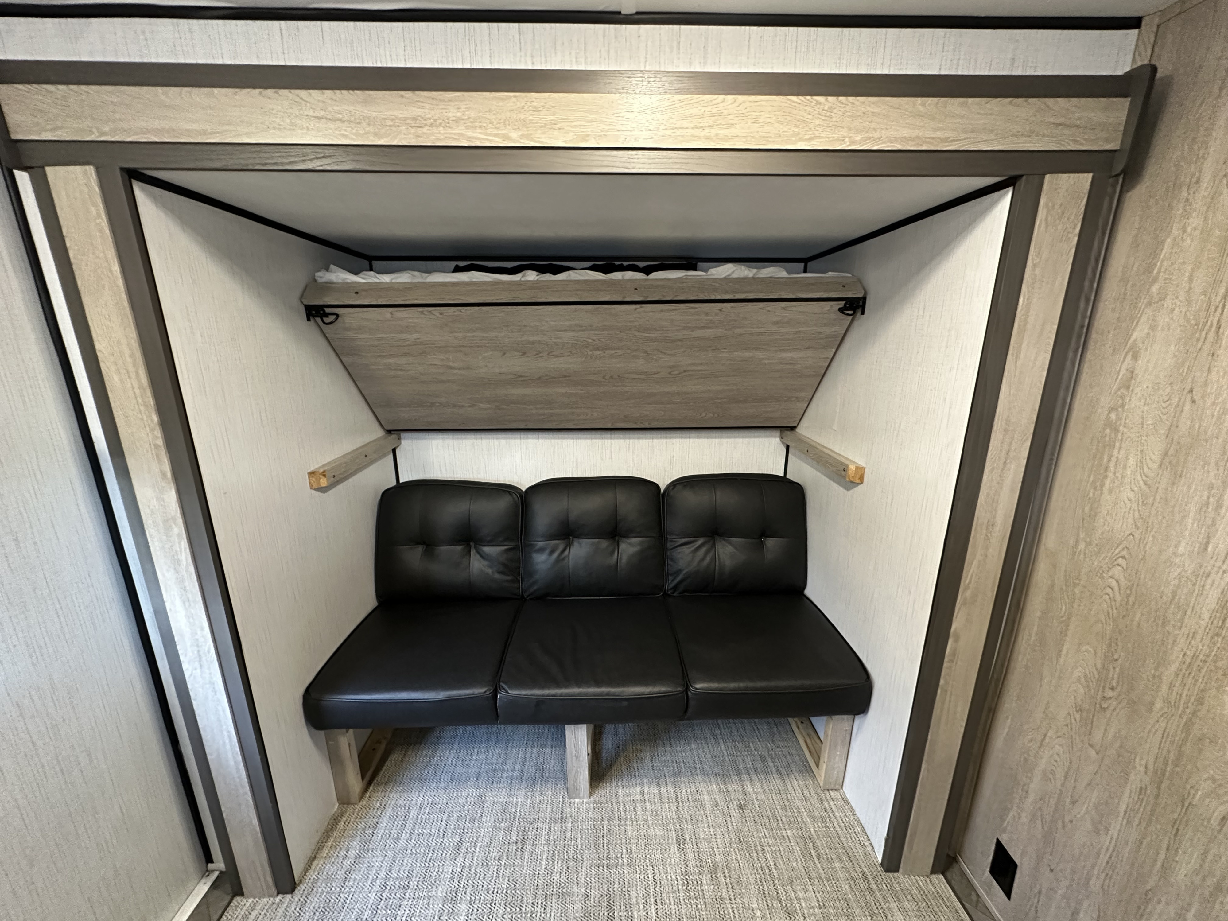 This RV rental features a versatile space with a black bench seat and a foldable bunk bed above, ideal for compact living.. Heartland Prowler 2022