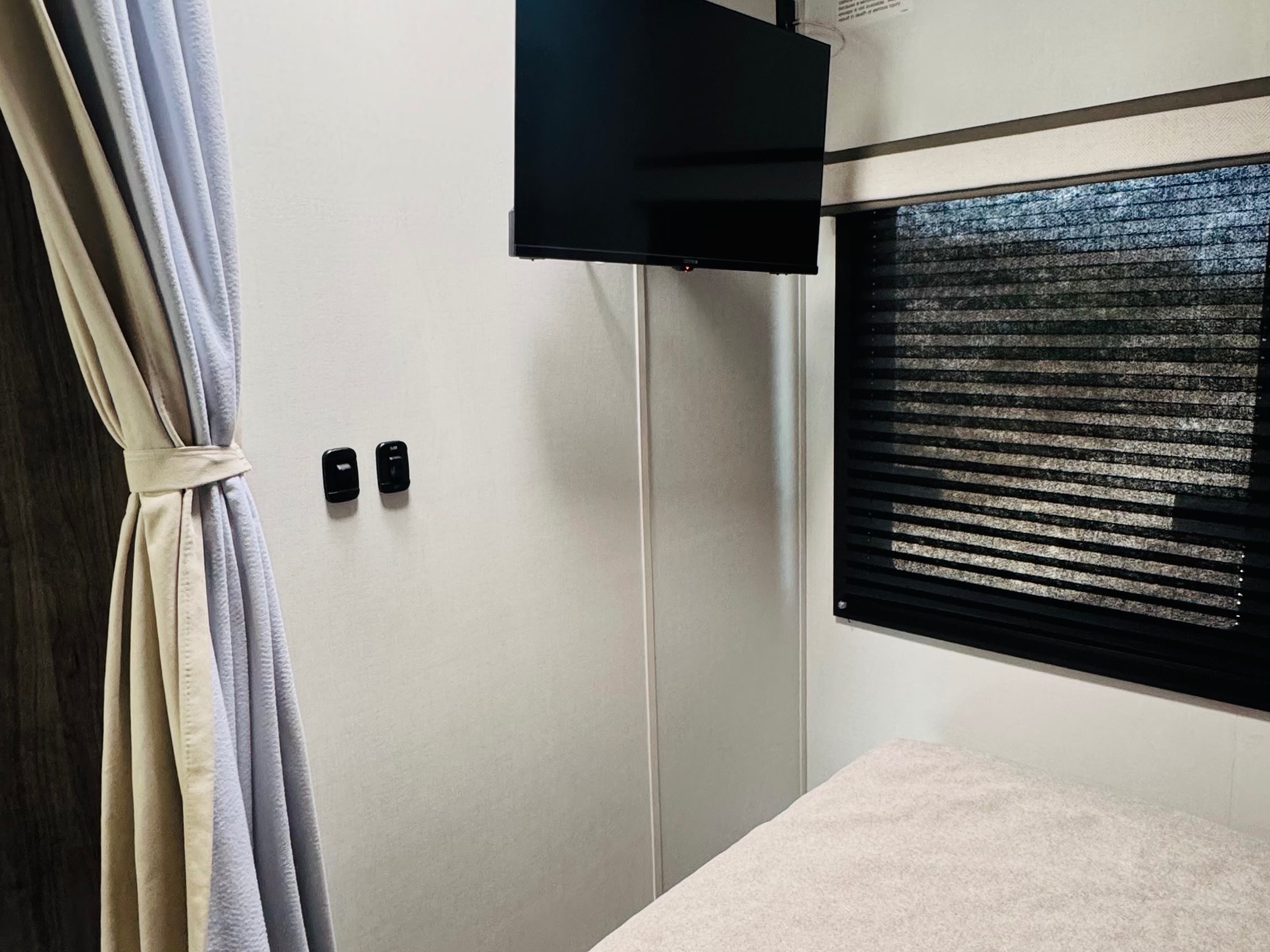 Experience comfort in your RV rental with a mounted TV, window blinds, tied-back curtains, and cozy sleeping area.. ENTEGRA ODYSSEY 22C 2026