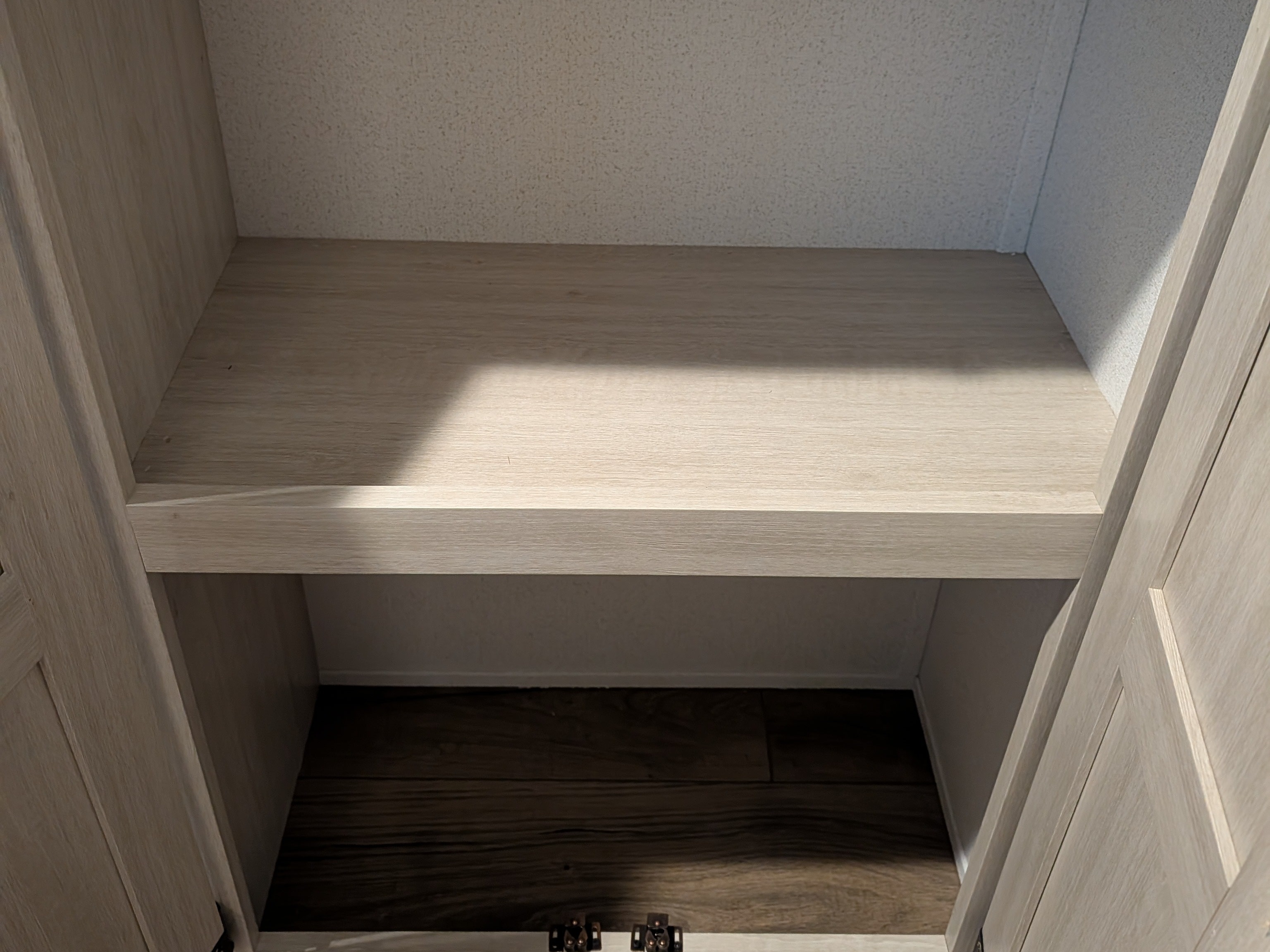 RV rental storage: Light wood cabinet interior with a shelf, textured walls, and dark flooring below.. Forest River 303BHCE Camping 2026
