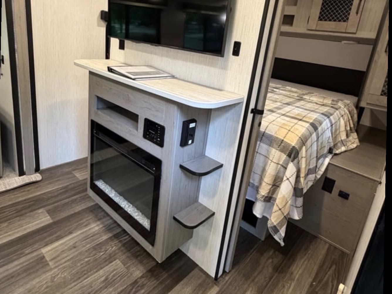 RV rental interior: Modern entertainment unit with TV & electric fireplace, adjacent cozy bedroom.. Heartland RVs Mallard 2022