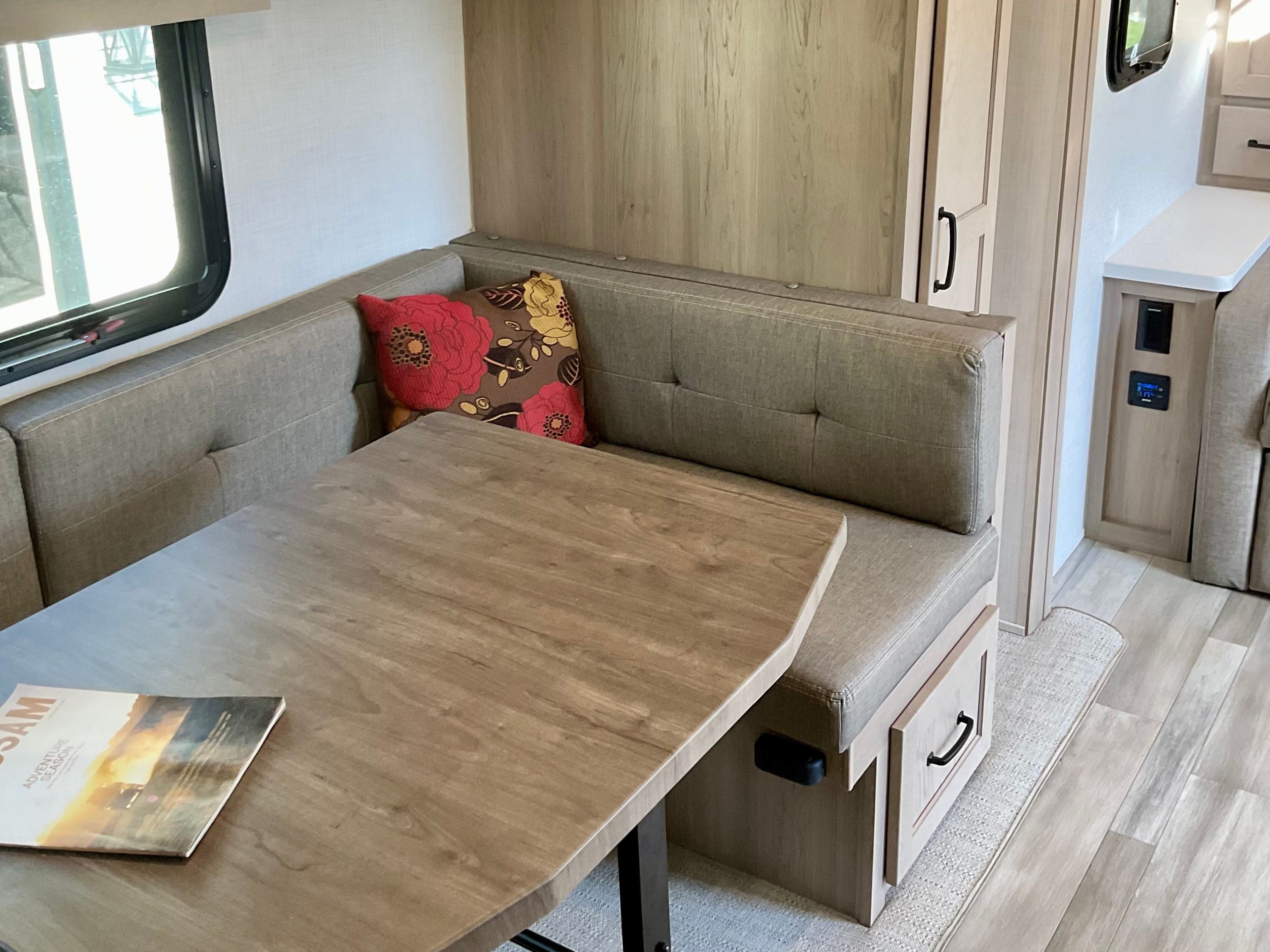 Bright rv rental interior featuring a modern dinette with upholstered benches, wood table, and overhead cabinets.. Forest River Rockwood Mini Lite 2024