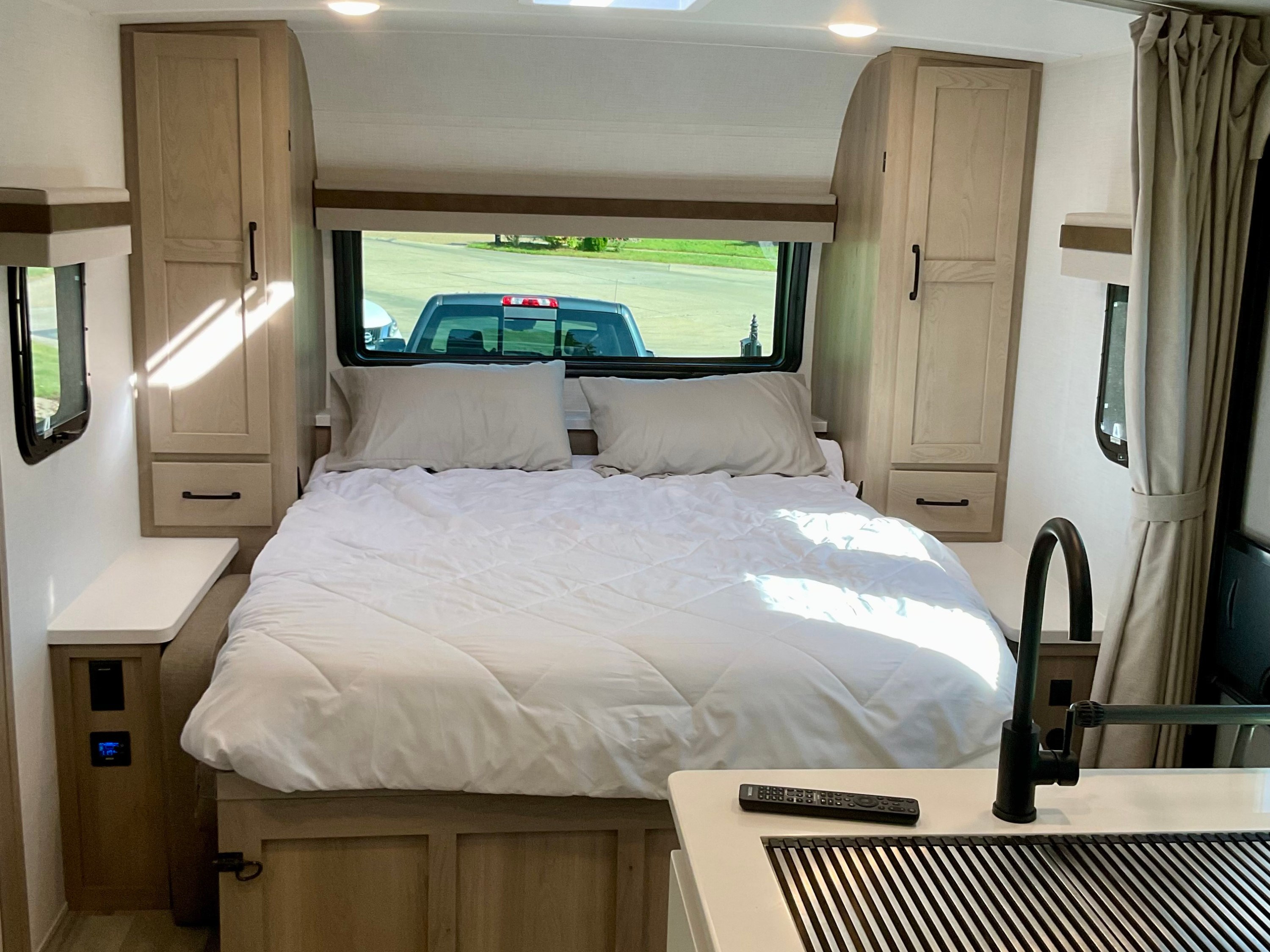 Cozy, modern RV rental bedroom with light wood tones, bright lighting, and integrated kitchenette for a compact, inviting space.. Forest River Rockwood Mini Lite 2024