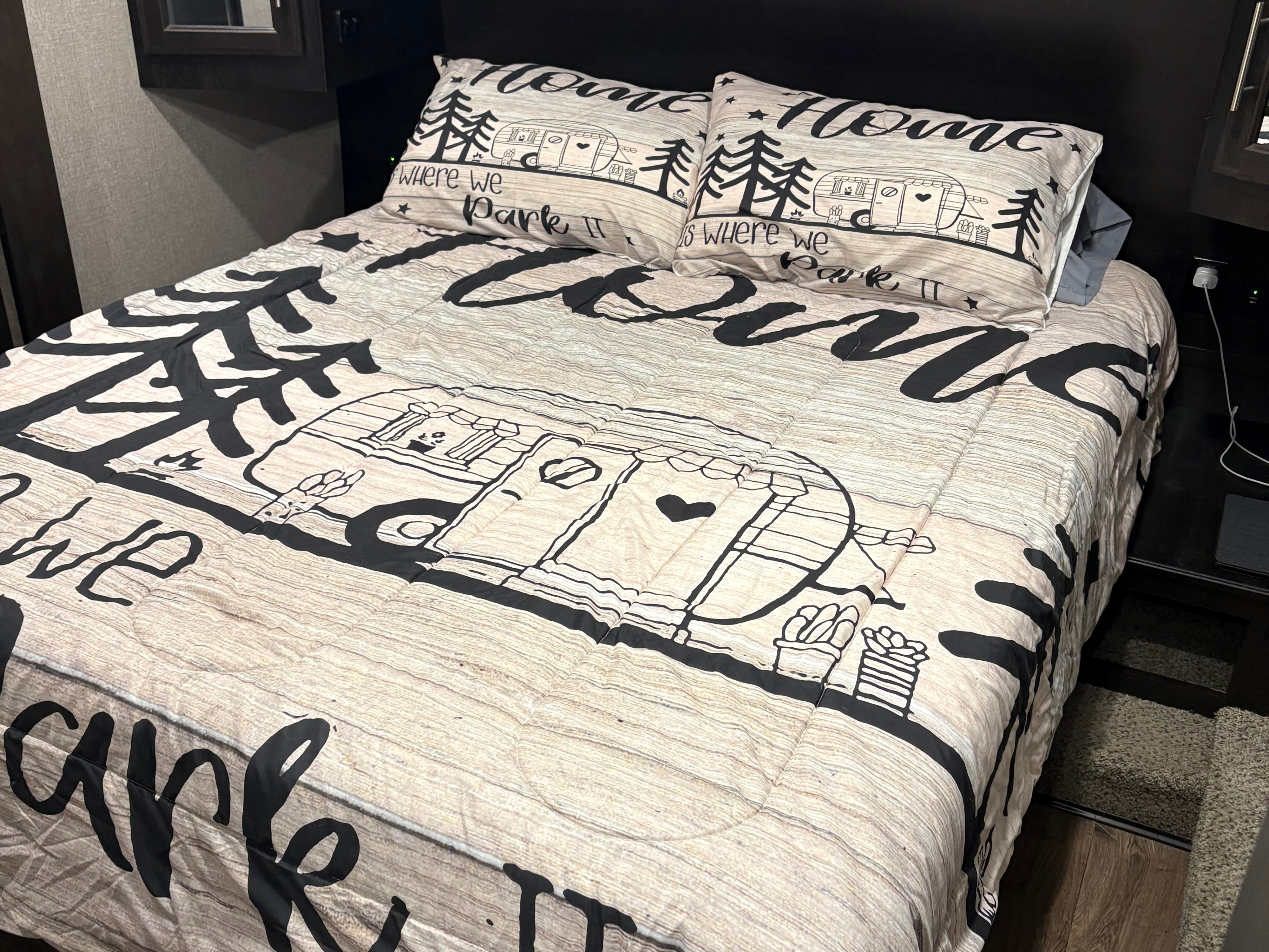 Themed camper bedding in an RV rental, showcasing "Home where we park it" with wood-grain detail.. Jayco Eagle HT 2021