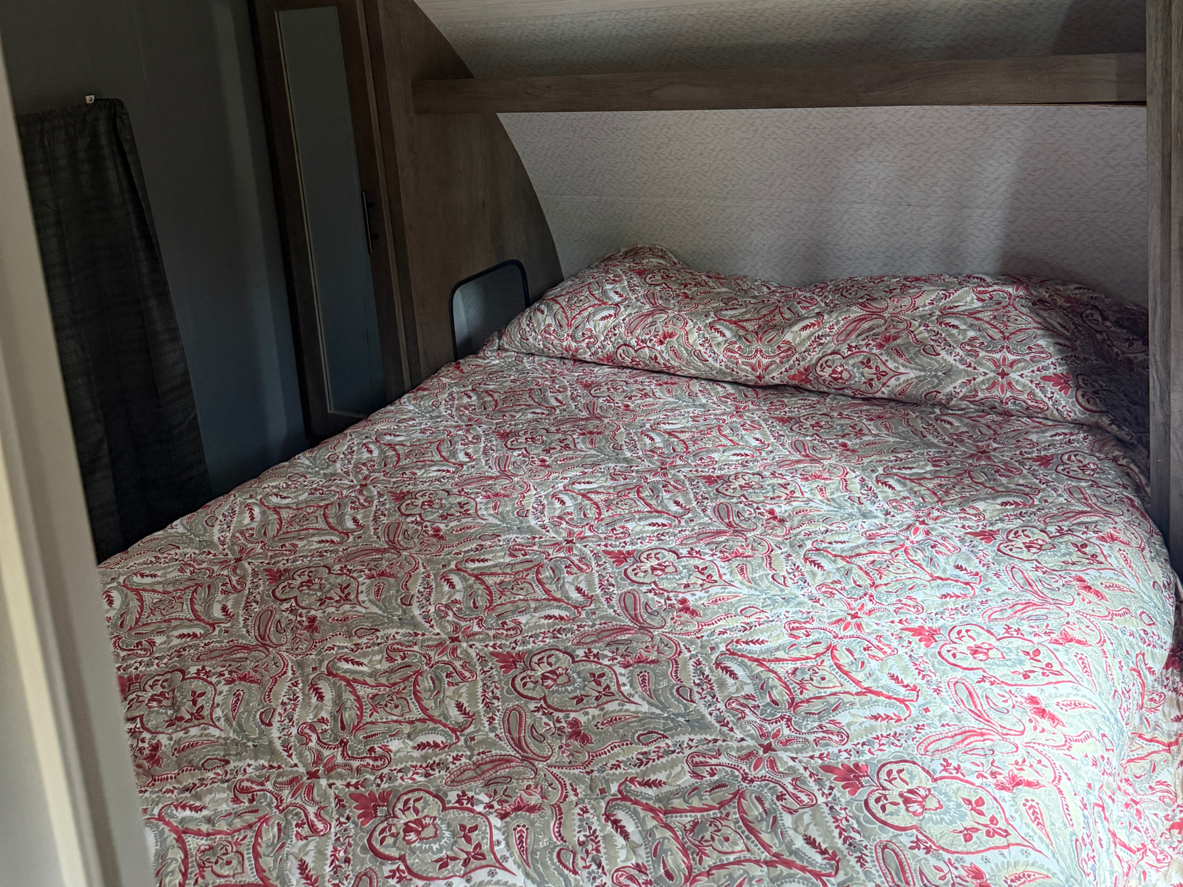 Cozy RV rental bedroom with a neatly made bed, featuring a red, grey, and white paisley patterned quilt and pillow.. Forest River Salem Cruise Lite 2022