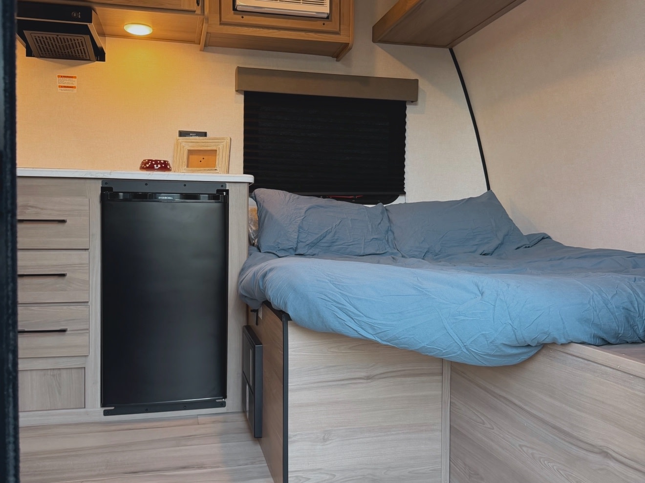 Comfortable RV rental interior showing a cozy bed, compact kitchen with fridge, and ample storage. Ideal for adventurers.. Keystone RV Coleman 2026
