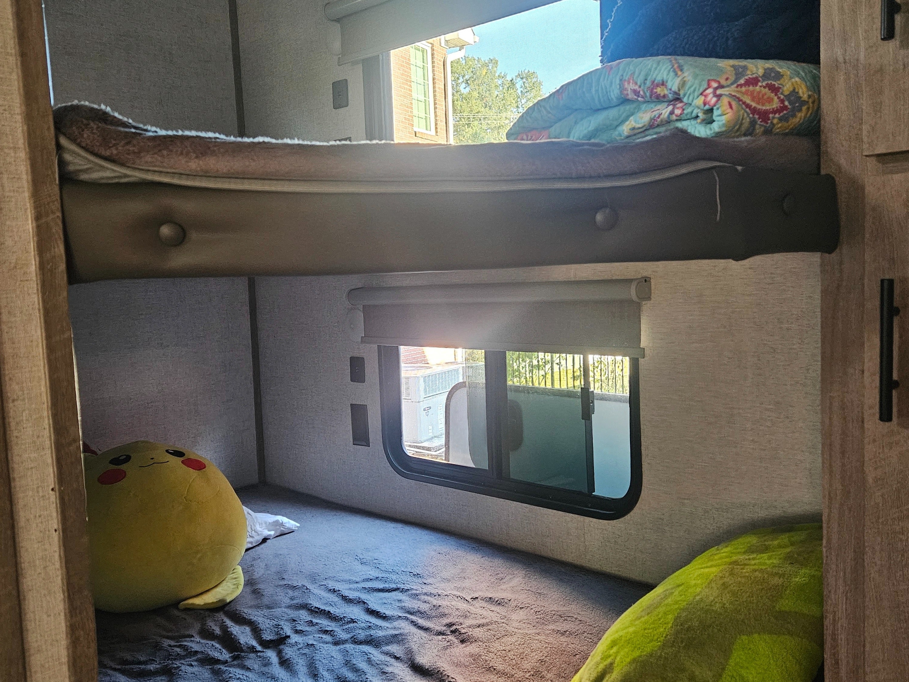 Cozy bunk beds in an RV rental, featuring windows, blankets, and a plush toy for a comfortable sleeping area.. Forest River Salem Hemisphere 2021