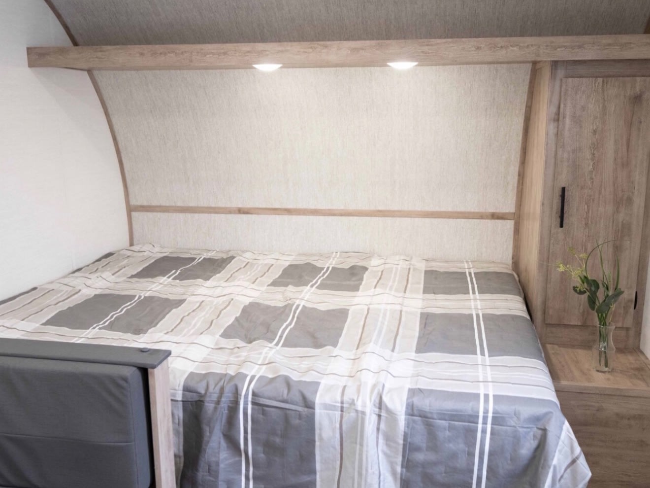 Inside an RV rental bedroom: a cozy full bed with plaid comforter, overhead lights, and handy storage for your journey.. Gulf Stream Ameri-Lite LE 2025