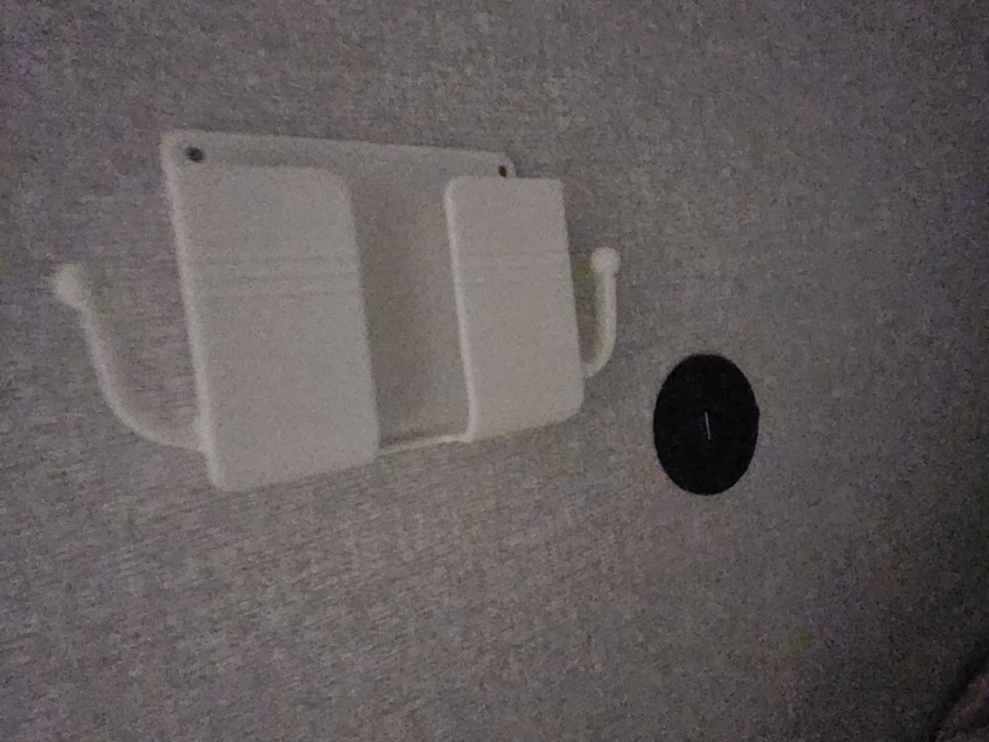 RV rental: Wall-mounted device holder with hooks & a black power port on a textured wall. Organize and charge electronics while traveling.. Jayco Jay Feather Air SL 2026