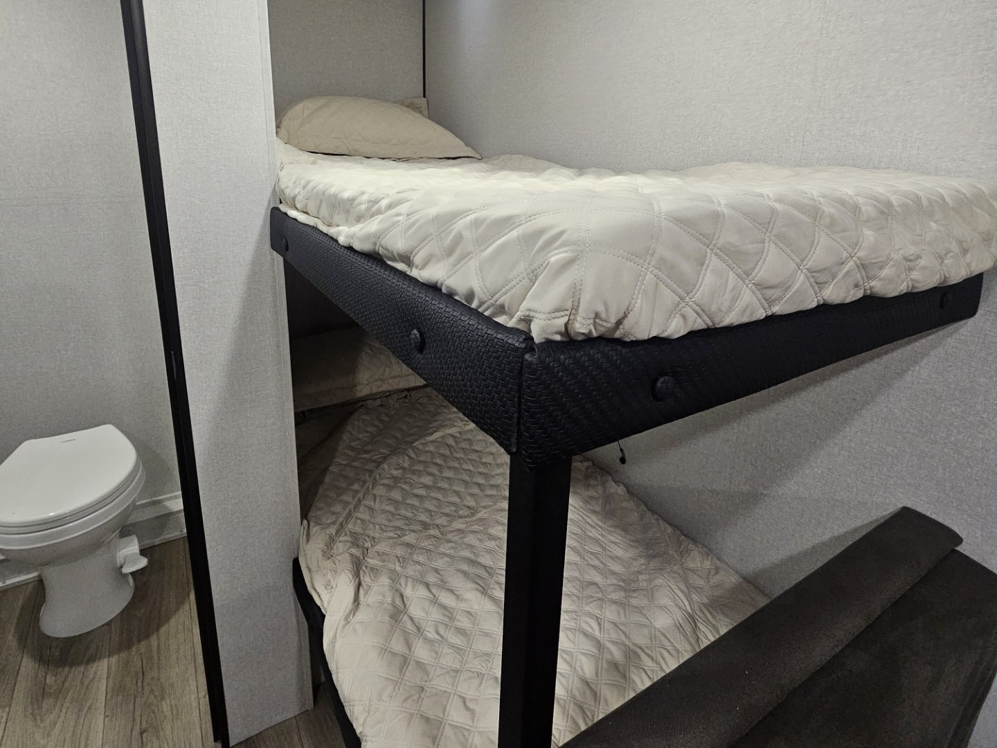 RV rental bunk beds with quilted bedding & a compact toilet, showcasing a cozy, functional interior for travel.. Jayco Jay Feather Air SL 2026