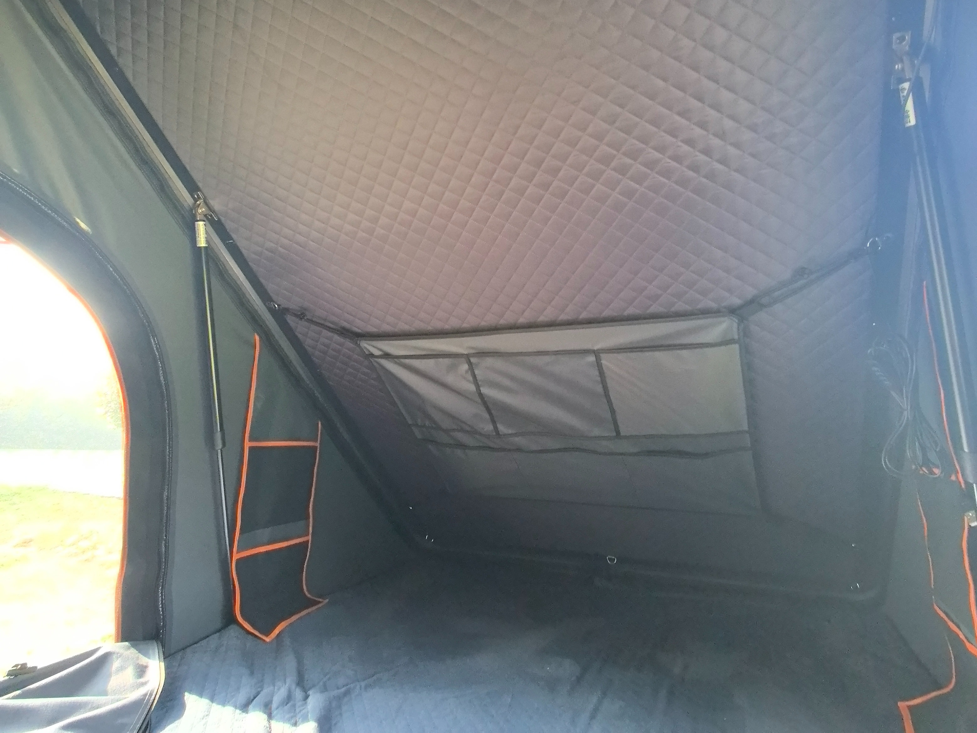 Cozy RV rental adventure: Inside a roof-top tent with a quilted ceiling, organized storage, and an inviting outdoor view.. Jeep Rubicon 4XE 2022