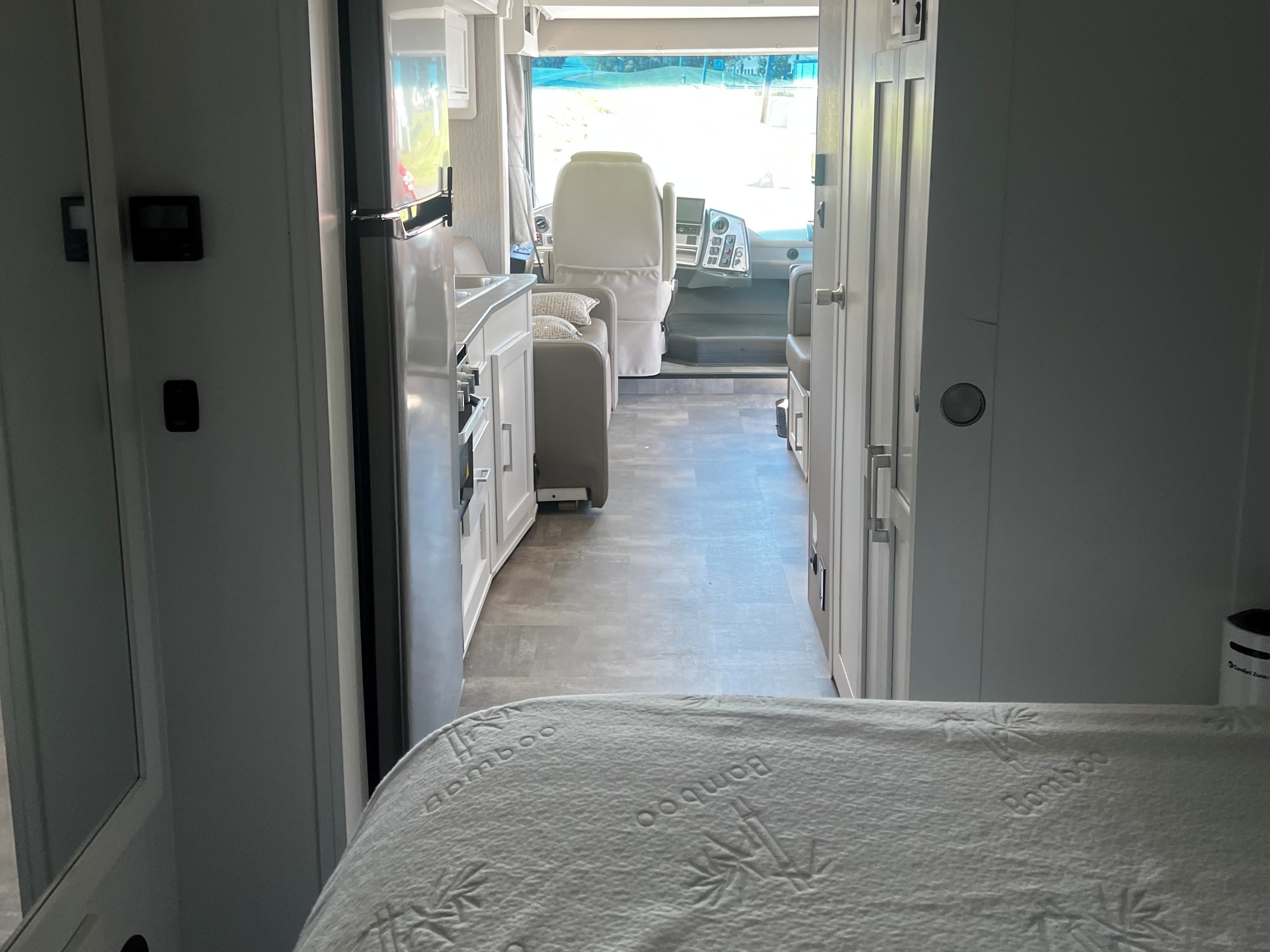 RV rental interior: Looking from the bedroom into a bright motorhome, past the kitchen to the cockpit, with a bamboo mattress.. Forest River Coachmen Pursuit 2022