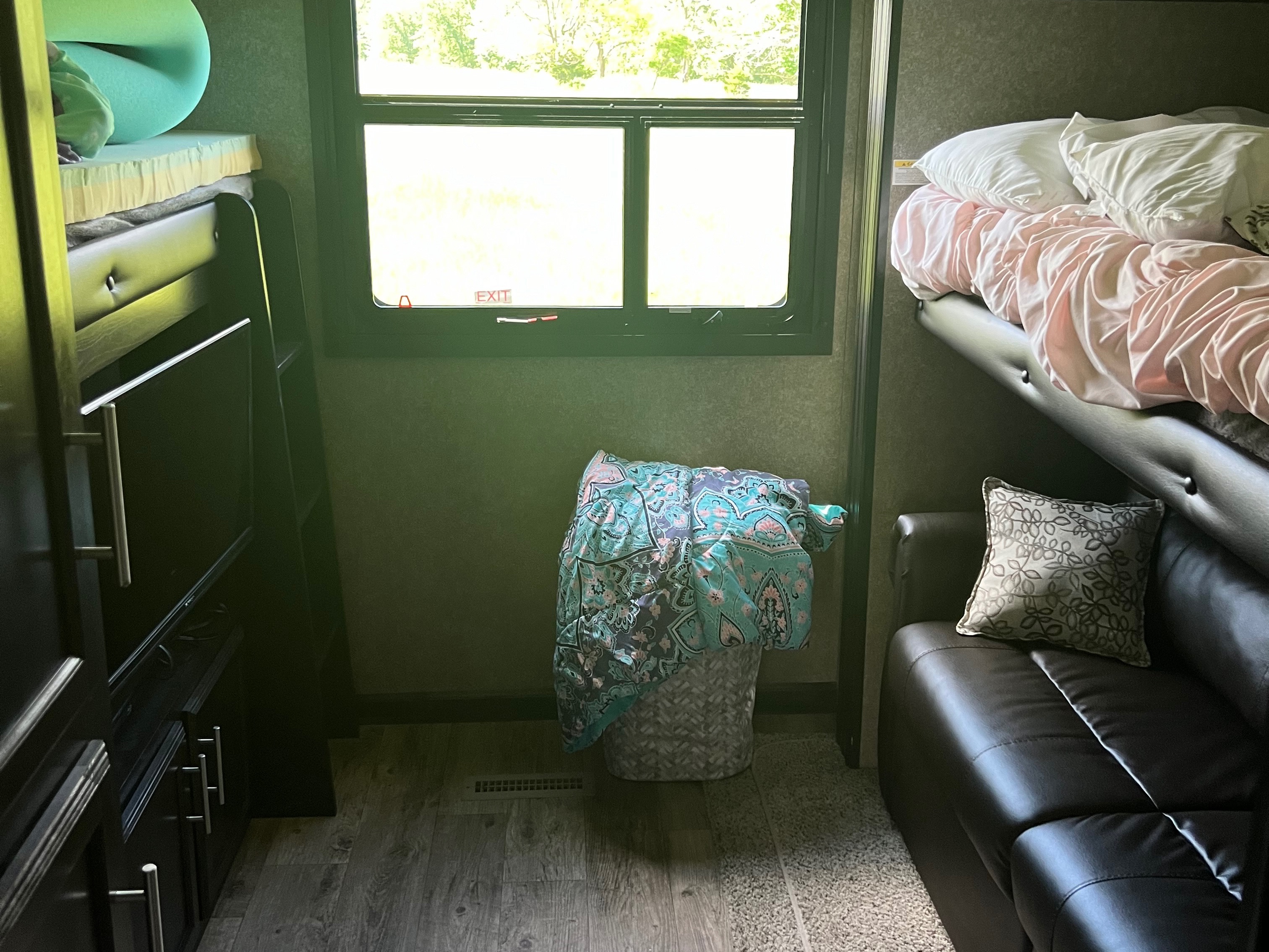 RV rental interior: bunk beds with bedding, a window with 'EXIT' label, and a comfortable sofa with a patterned pillow.. Jayco Eagle HT 2020