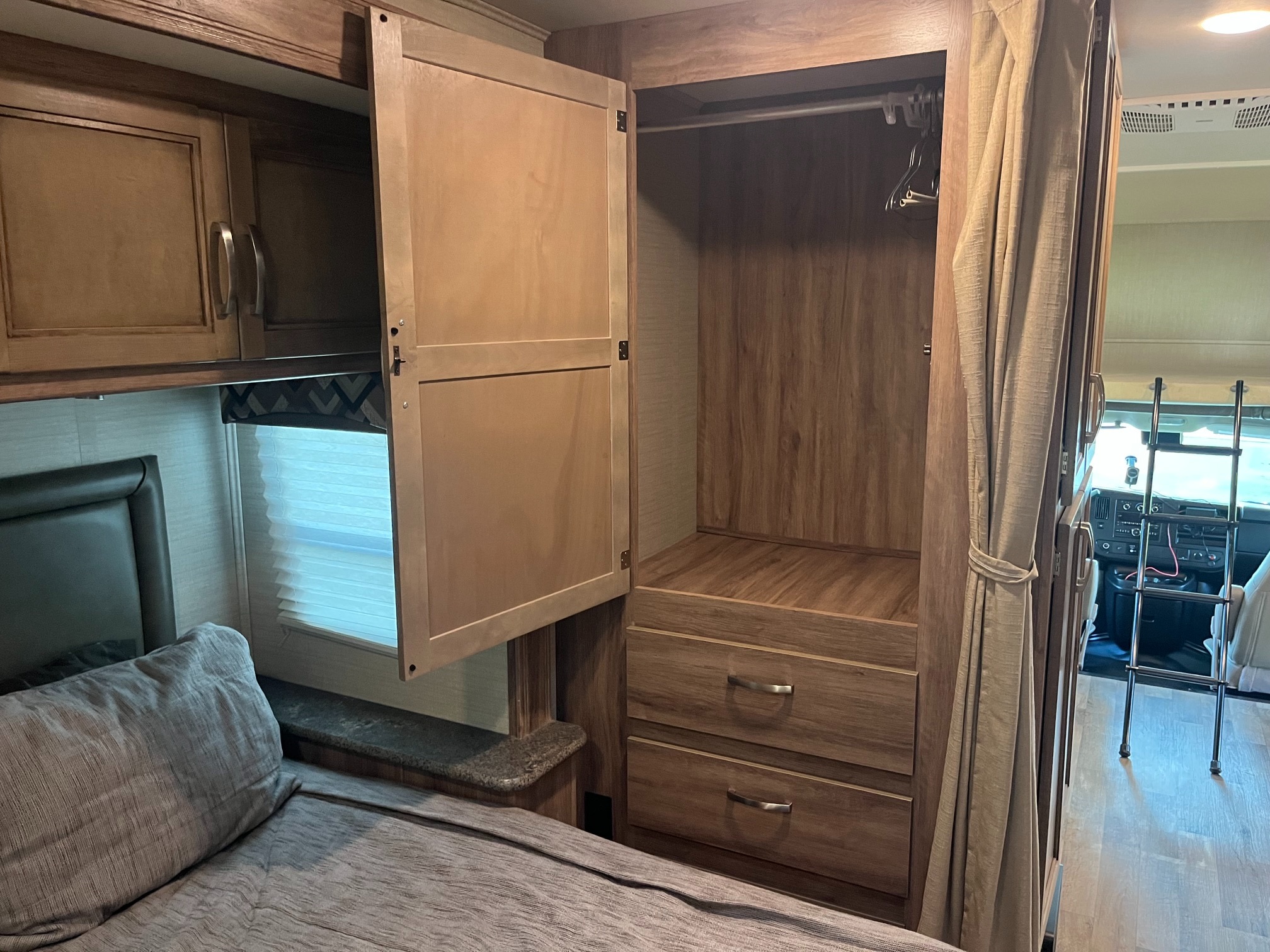 Explore this RV rental's bedroom area: a comfortable bed, overhead storage, and a wooden wardrobe with drawers and a hanger bar.. Jayco Redhawk SE 2019