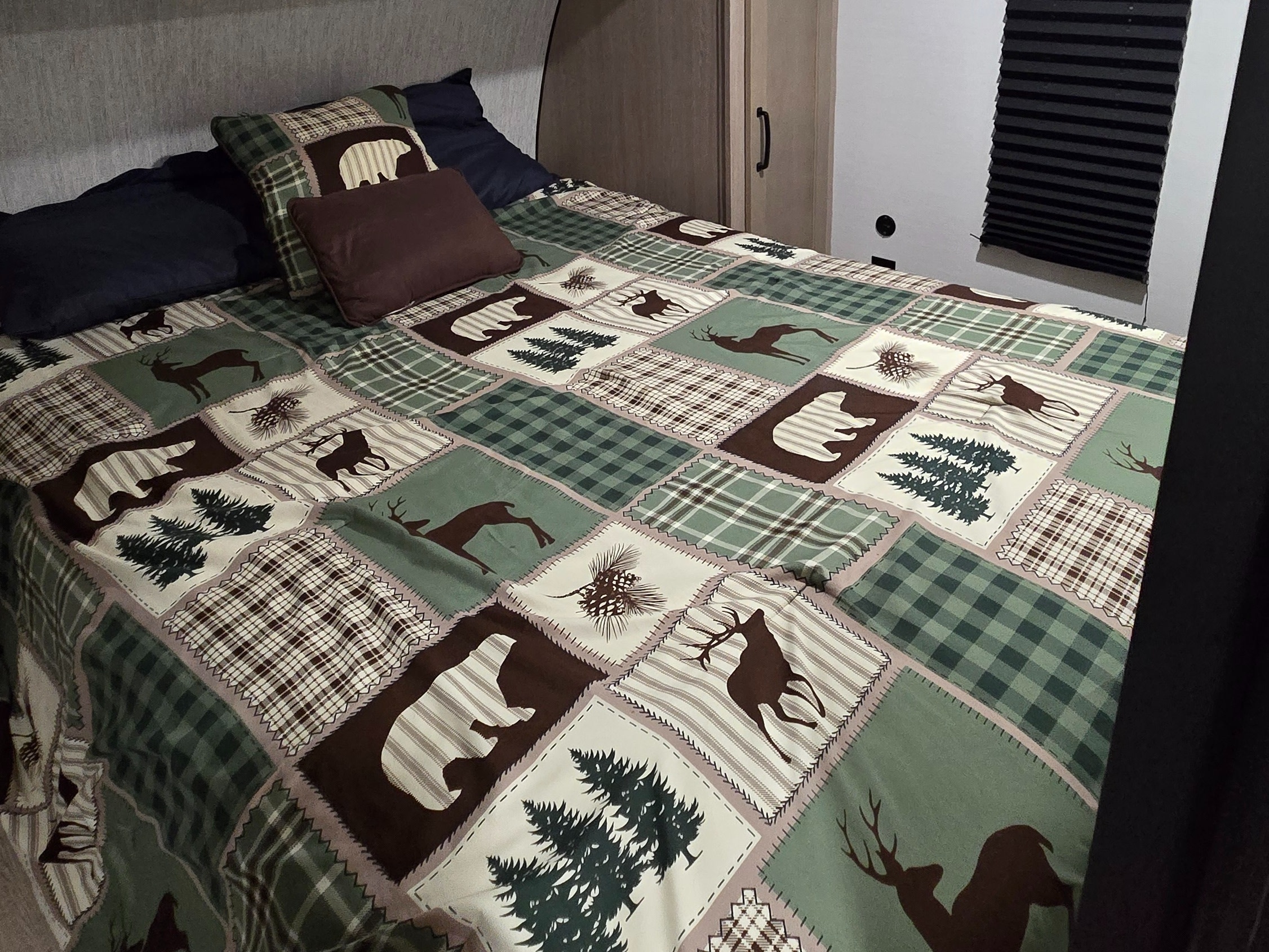 Cozy RV rental interior: bedroom with a rustic nature-themed quilt & pillows. Perfect for camping getaways.. Gulf Stream Grand River 2026