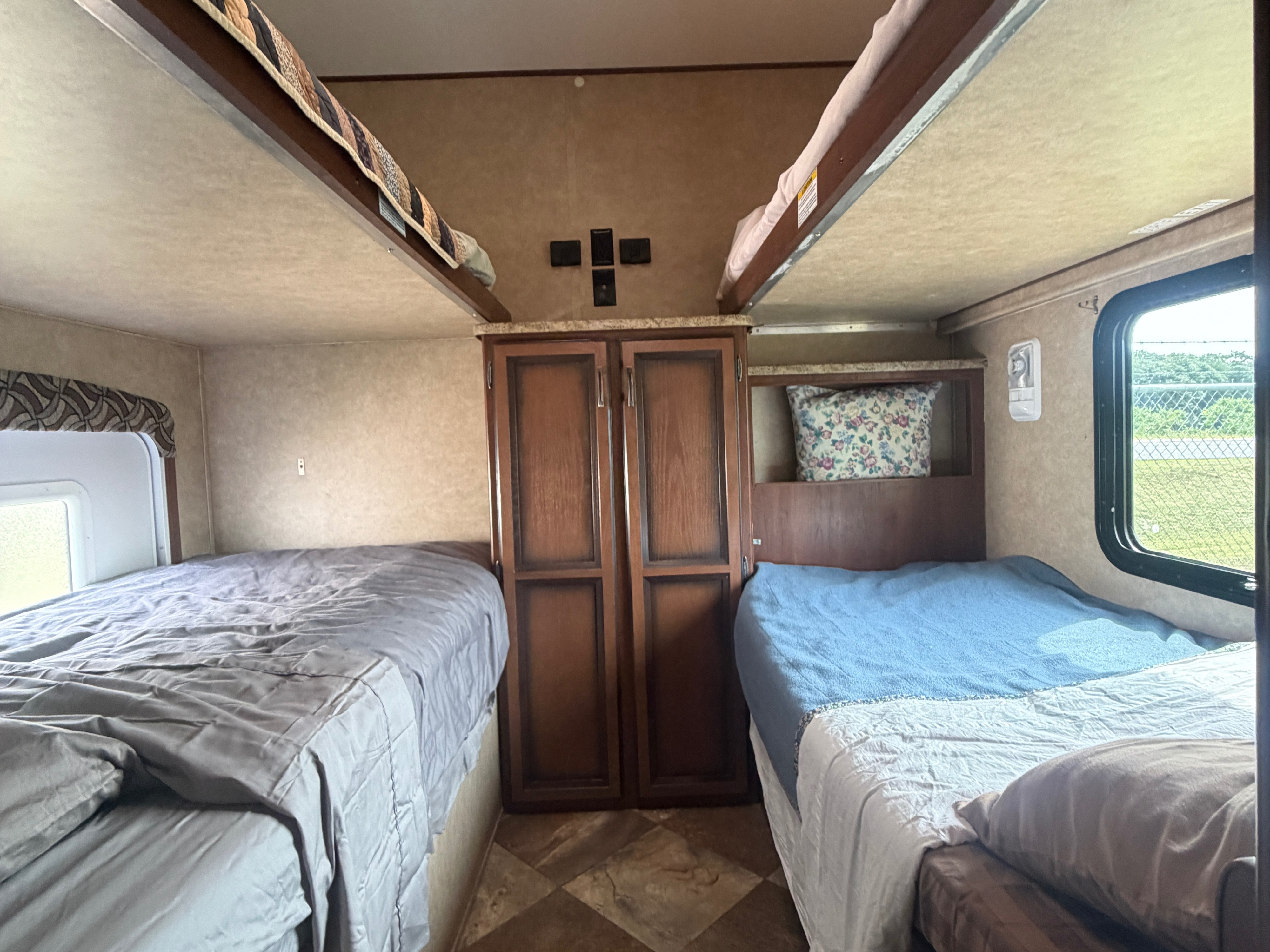 Cozy **RV rental** sleeping area with two lower beds, upper bunks, and central storage, perfect for family adventures.. Crossroads RV Zinger 2014