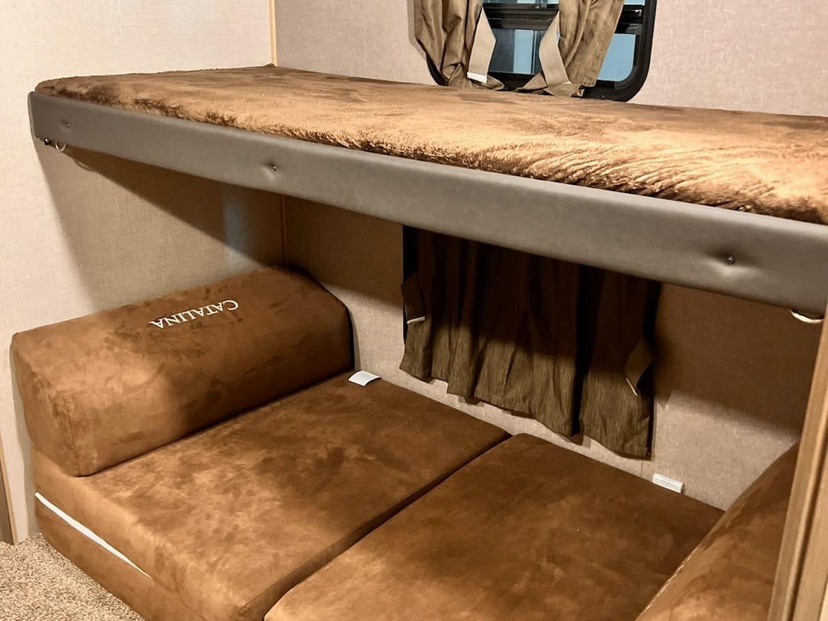 Cozy RV rental interior featuring a bunk bed, window, and "CATALINA" branded convertible seating below.. Coachmen Catalina 2022