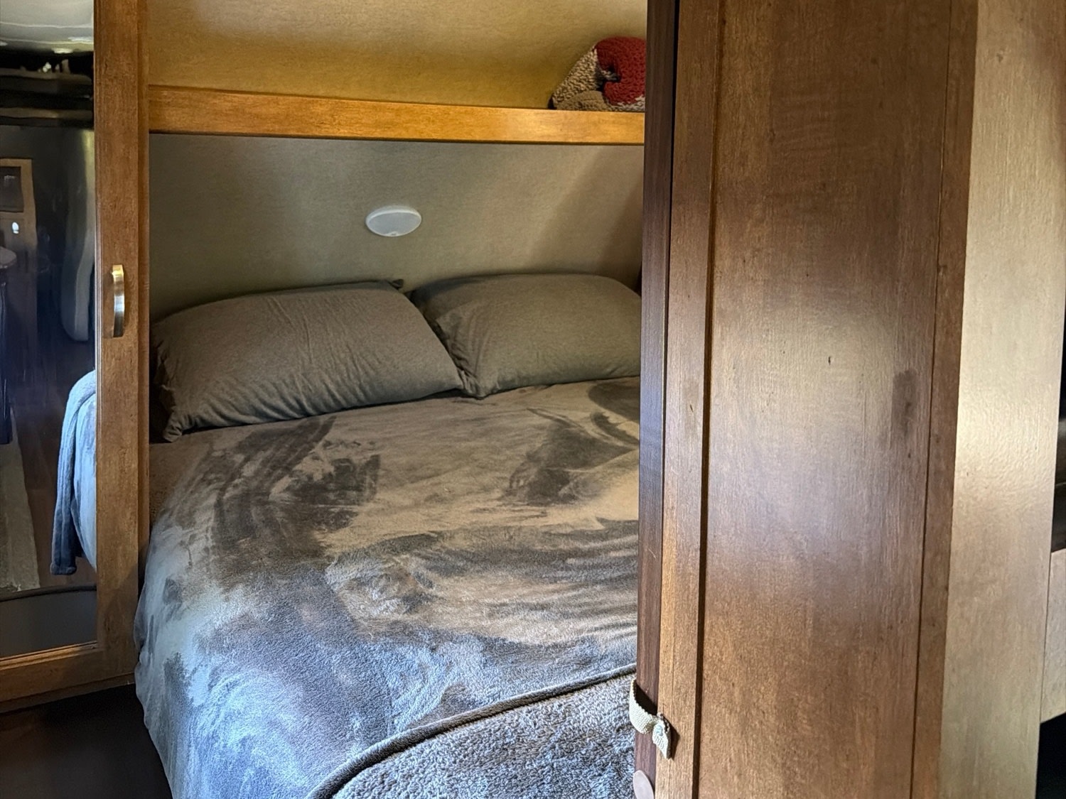 Cozy RV rental bedroom features a comfy bed with storage shelf and wooden cabinetry, perfect for your next adventure.. Forest River T27TDSS 2017