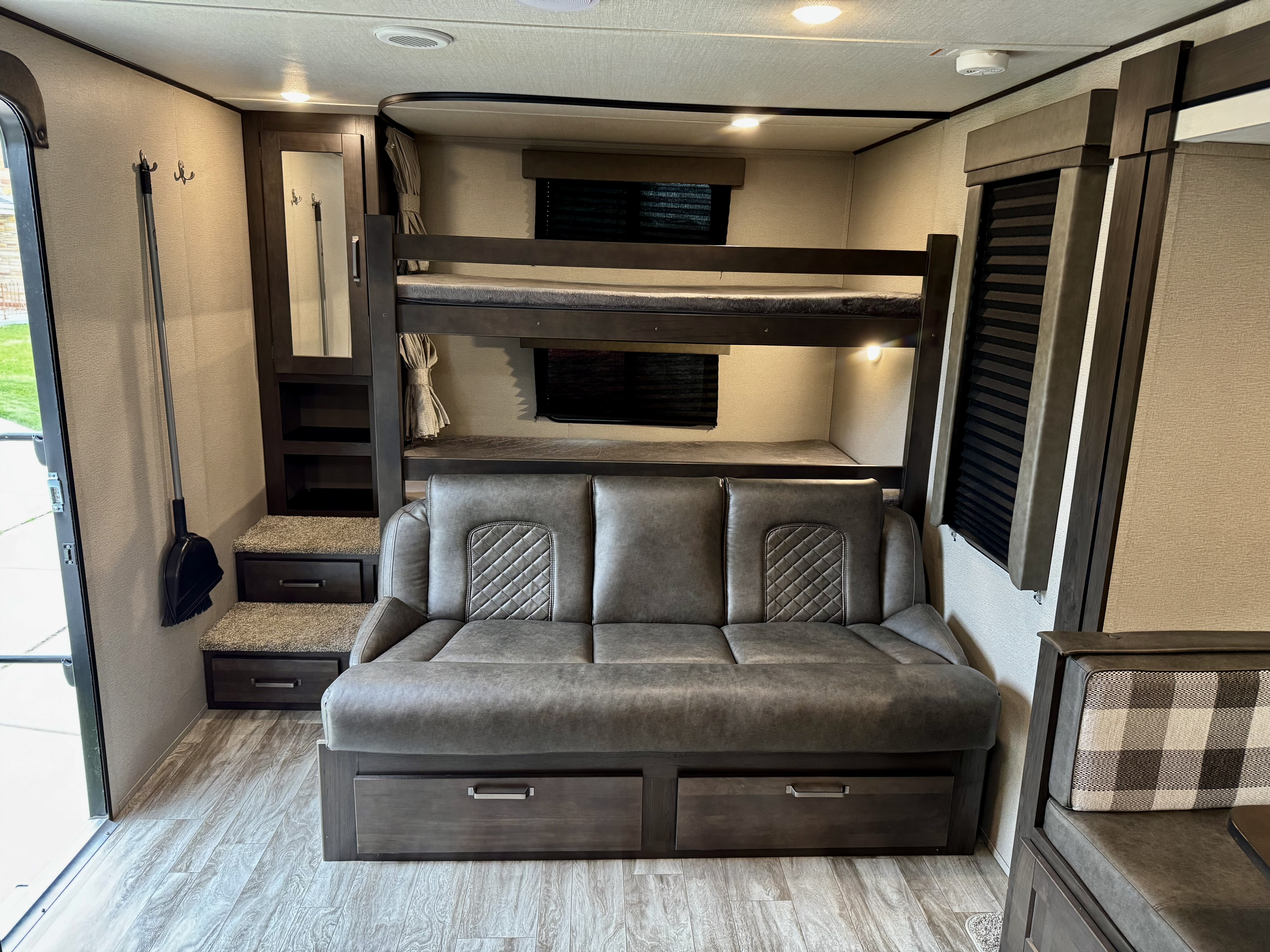 Cozy RV rental interior featuring comfortable bunk beds, a sofa with storage, and dinette seating, ready for your next adventure.. Grand Design Transcend Xplor 2022