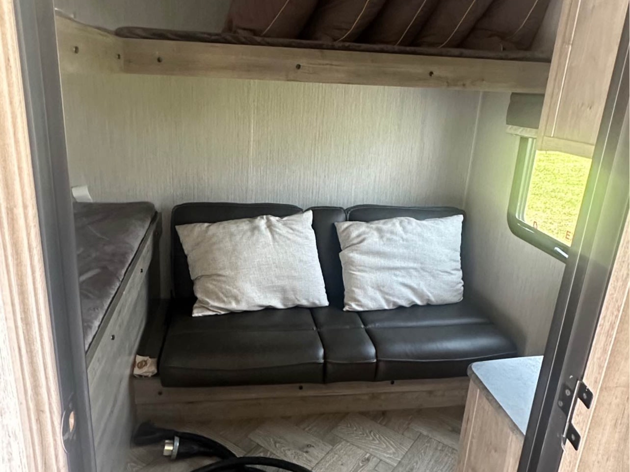 This RV rental interior features compact bunk beds, a comfortable sofa, and a window for scenic travel.. Forest River Palomino Puma 2021