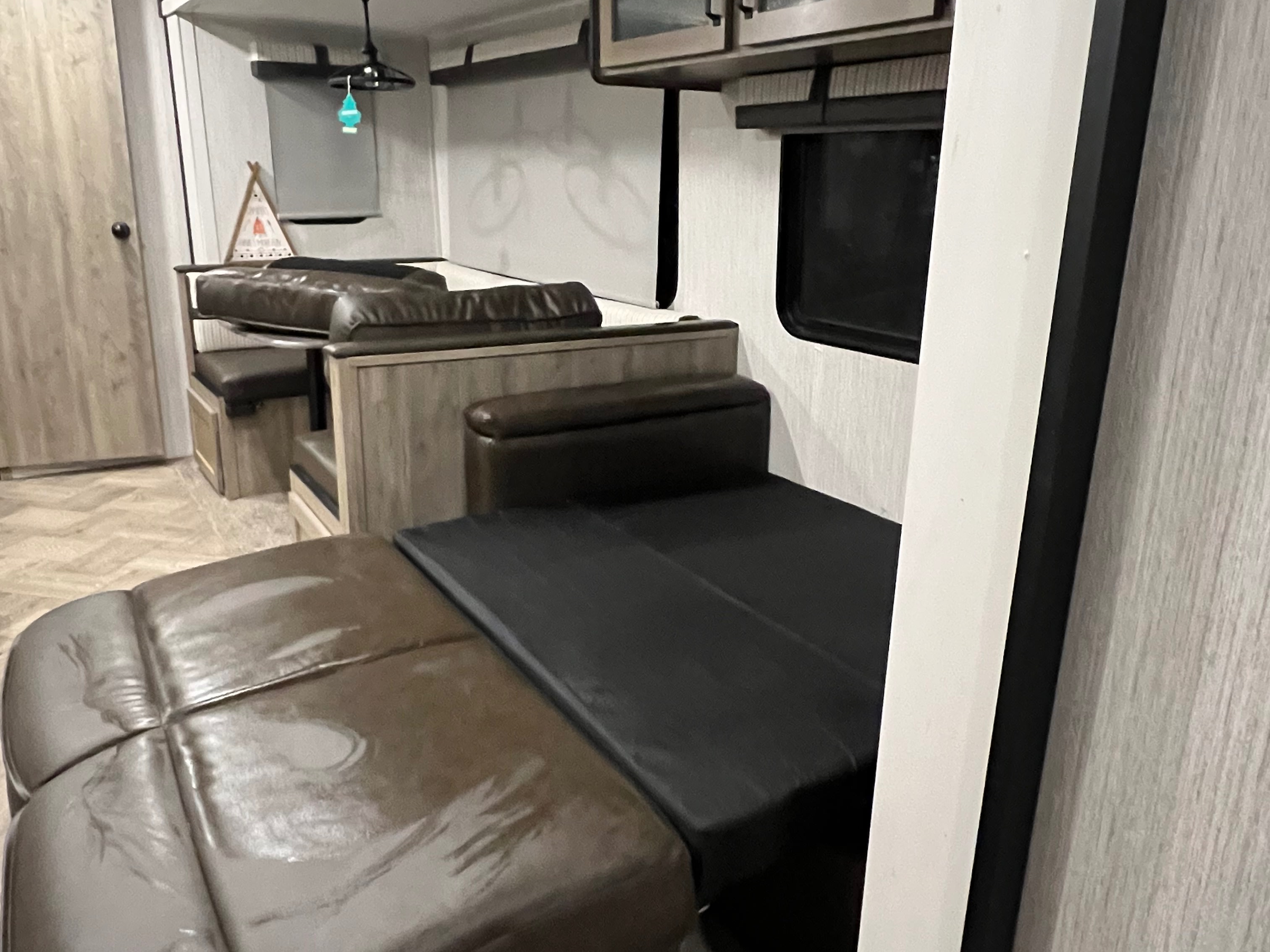 RV rental interior: a dinette converts to a bed, with light wood walls & modern overhead lights.. Forest River Palomino Puma 2021