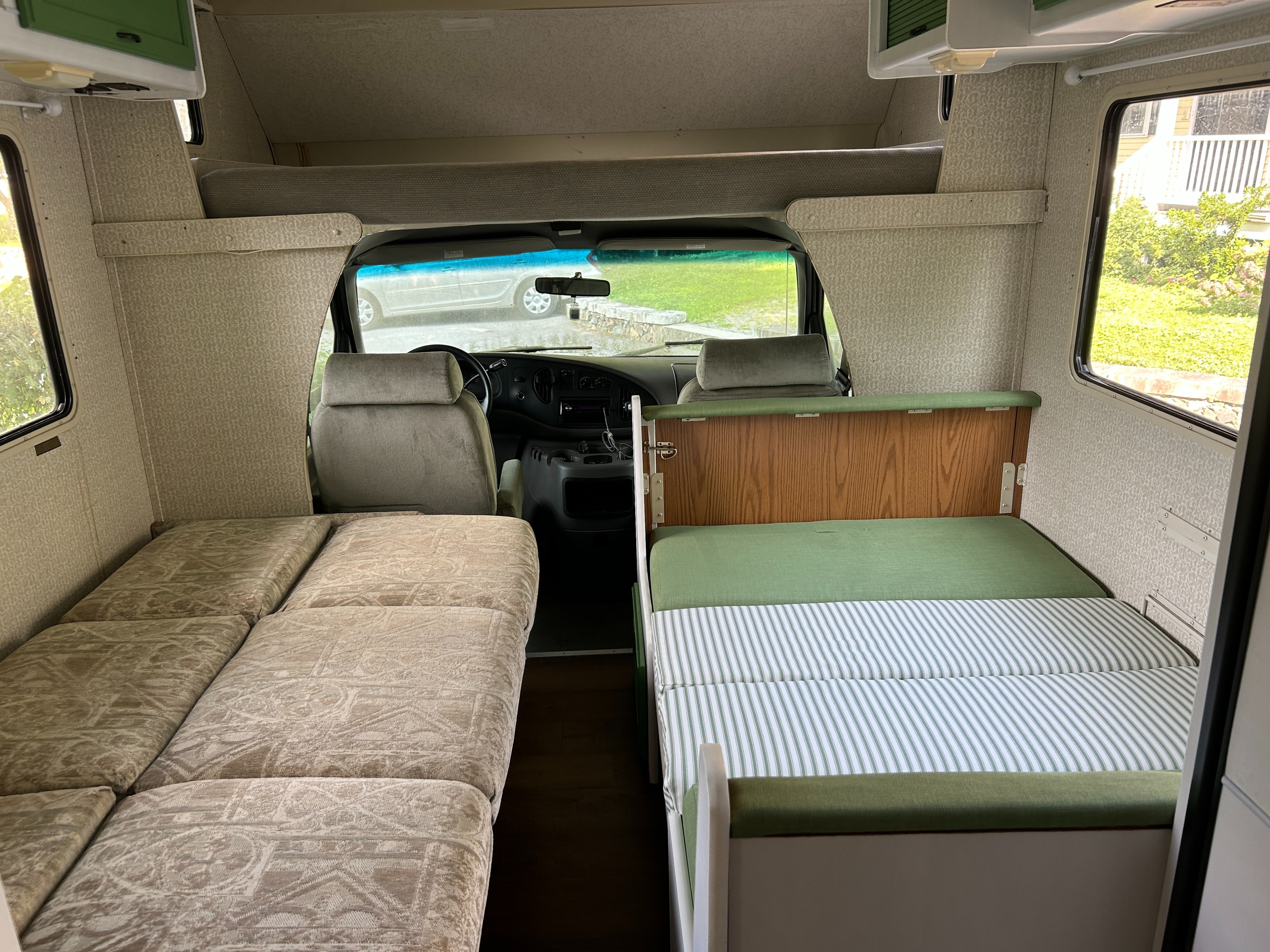 Inside a compact RV rental, featuring two distinct bed areas with patterned and striped cushions for travelers.. Winnebago Minnie 1998