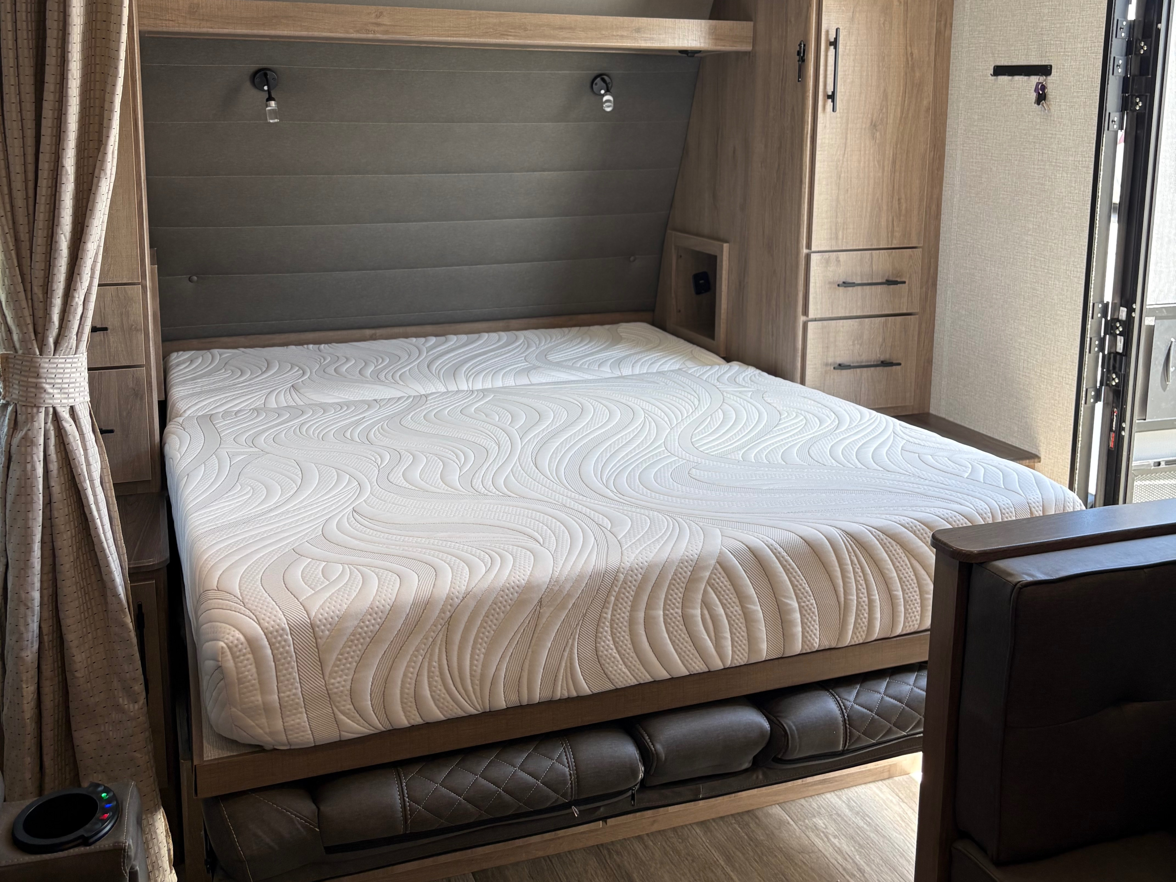 RV rental bedroom: a queen bed with quilted mattress, pull-out sofa below, wardrobe, and reading lights.. Grand Design Imagine XLS 2023