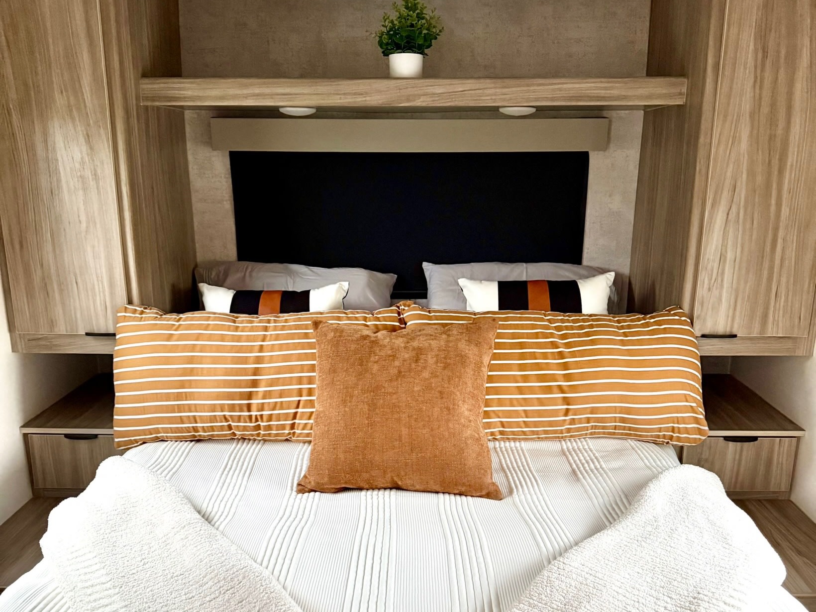 Our RV rental offers a cozy, comfortable bedroom with a neatly made bed, stylish pillows, and convenient storage.. Winnebago Access 2024
