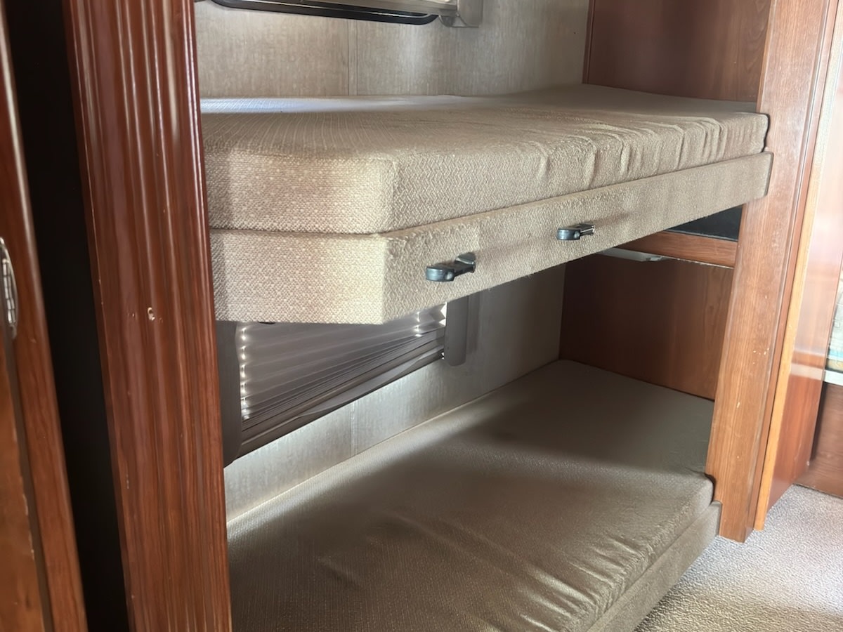 These RV rental bunk beds feature two light-colored mattresses, one above the other, within a wood-paneled interior.. Fleetwood Fiesta 2009