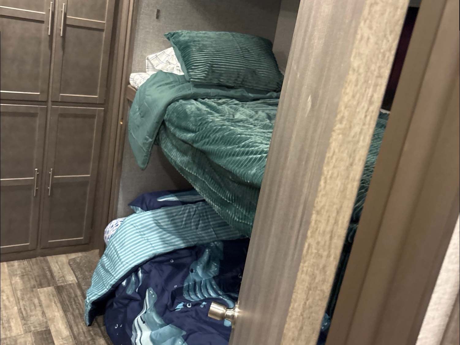Cozy rv rental bunk beds with teal and blue bedding. Dark cabinetry and wood-look flooring enhance this compact interior.. Crossroads RV Volante 2021