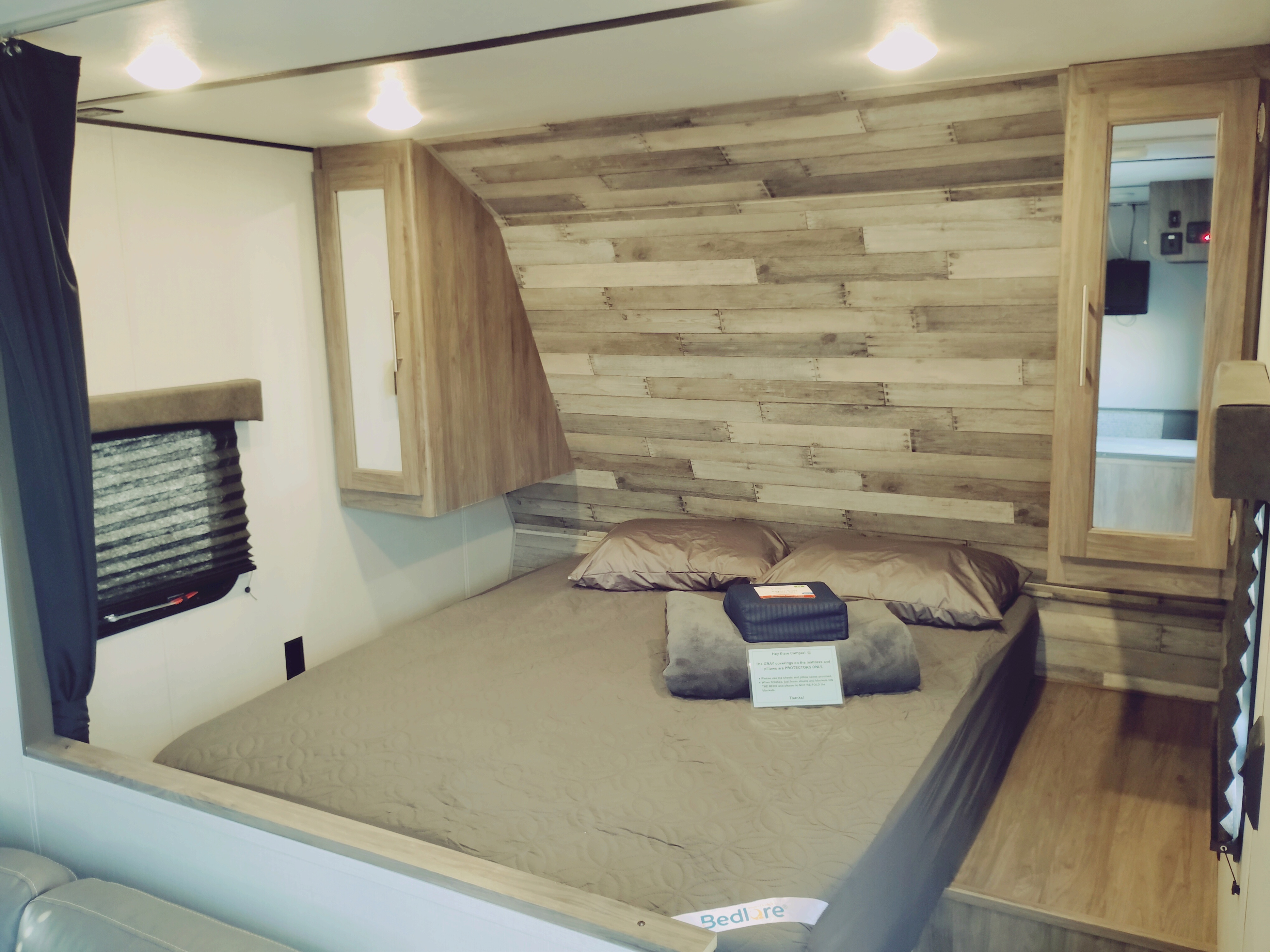 Step into this cozy RV rental bedroom, featuring a comfortable bed, stylish wood accent wall, and practical storage.. Crossroads RV Zinger Lite 2020