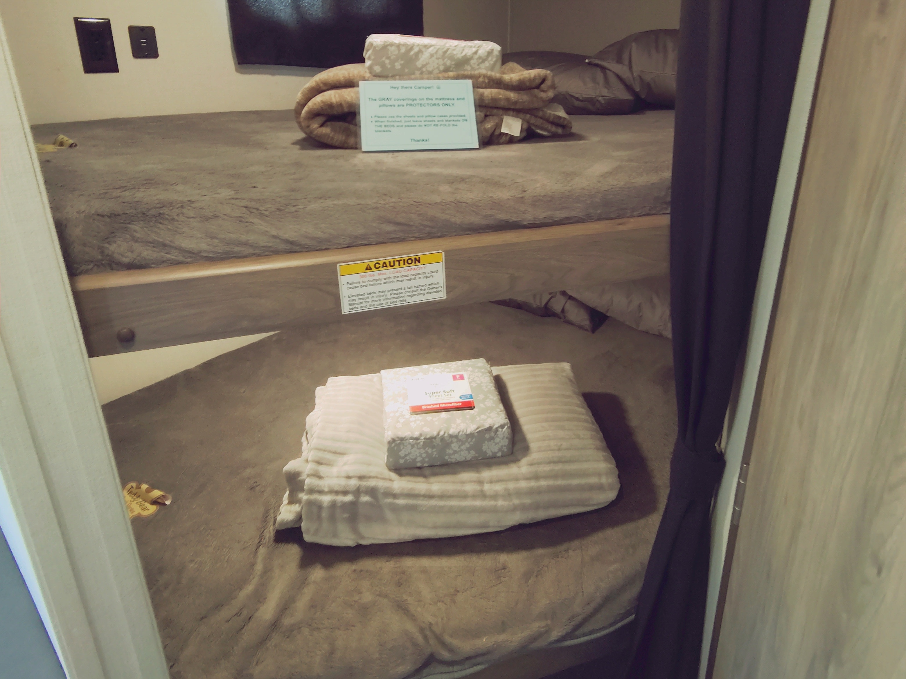 RV rental bunk beds with fresh bedding, a sheet set, and important caution signs about bed capacity and safety.. Crossroads RV Zinger Lite 2020