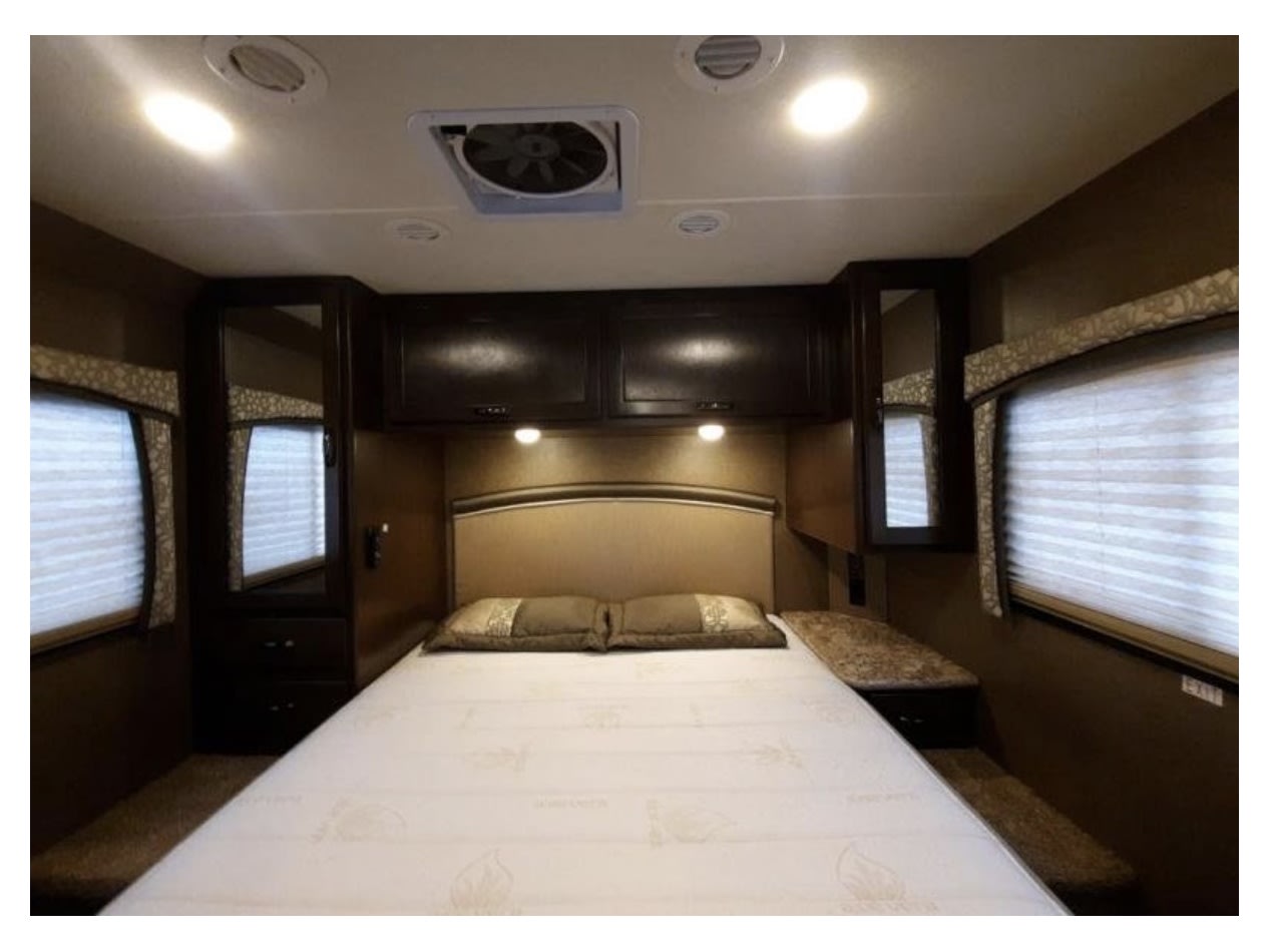 Cozy rv rental bedroom with a queen bed, overhead storage, side cabinets, windows with blinds, ceiling fan, and recessed lighting.. Thor Chateau 2020