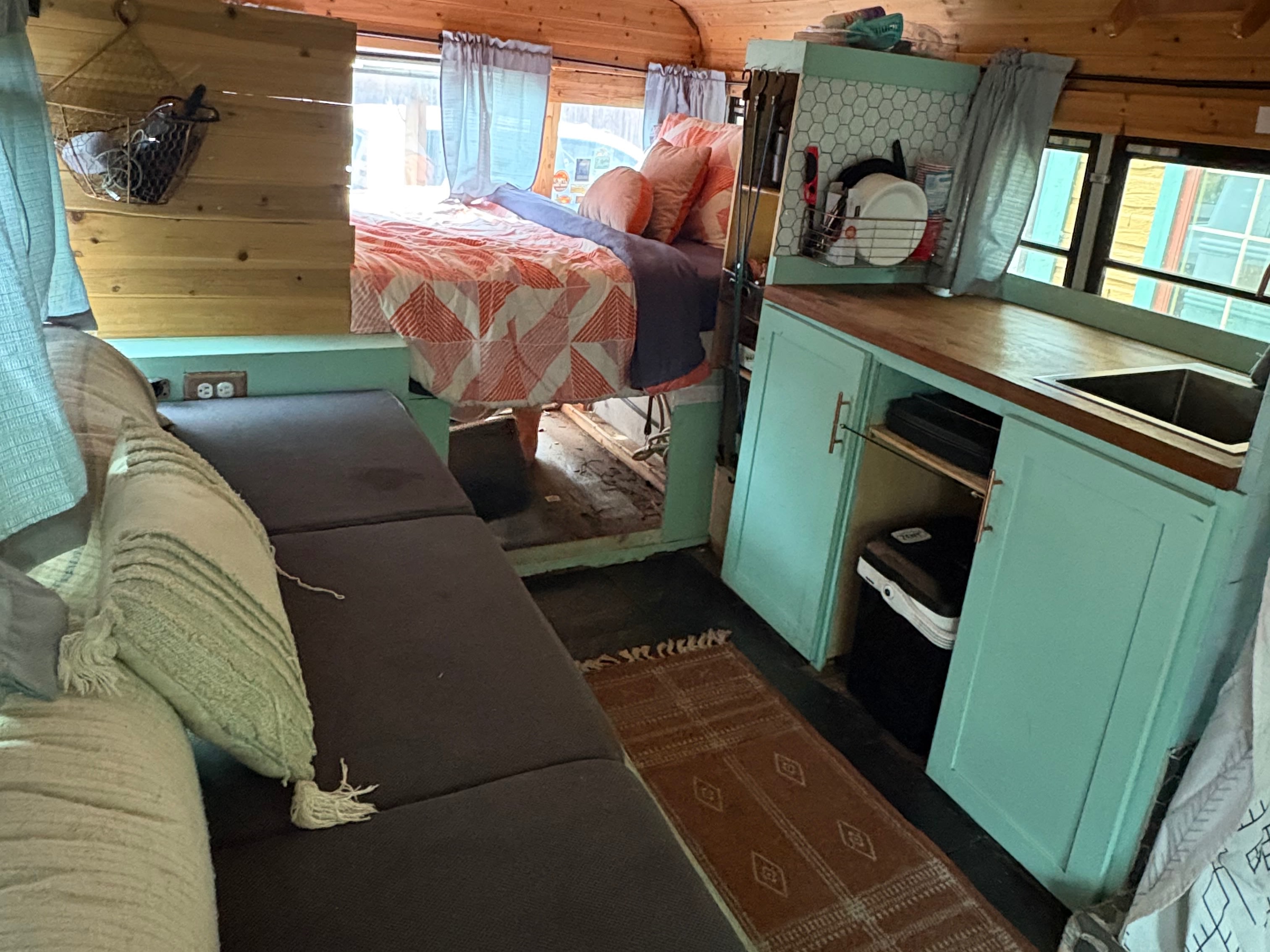 RV rental bus conversion: warm interior with bed, compact kitchen, and sofa lounge. Cozy, functional living space.. Gmc Savanna 2001
