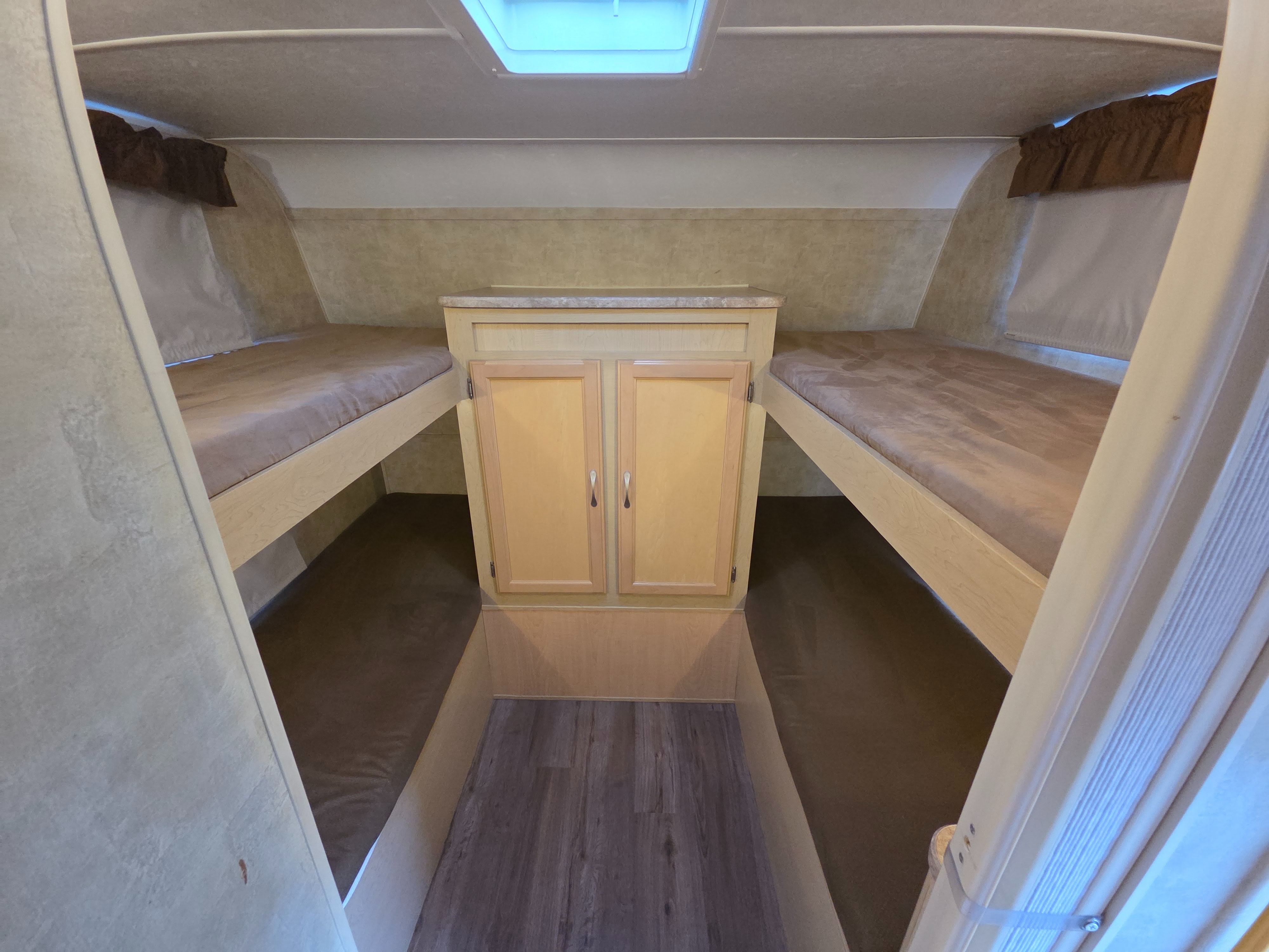 This RV rental interior features two bunk beds with mattresses, a central storage cabinet, and a skylight, offering practical camper accommodation.. Aerolite Aerolite Trailer 2007