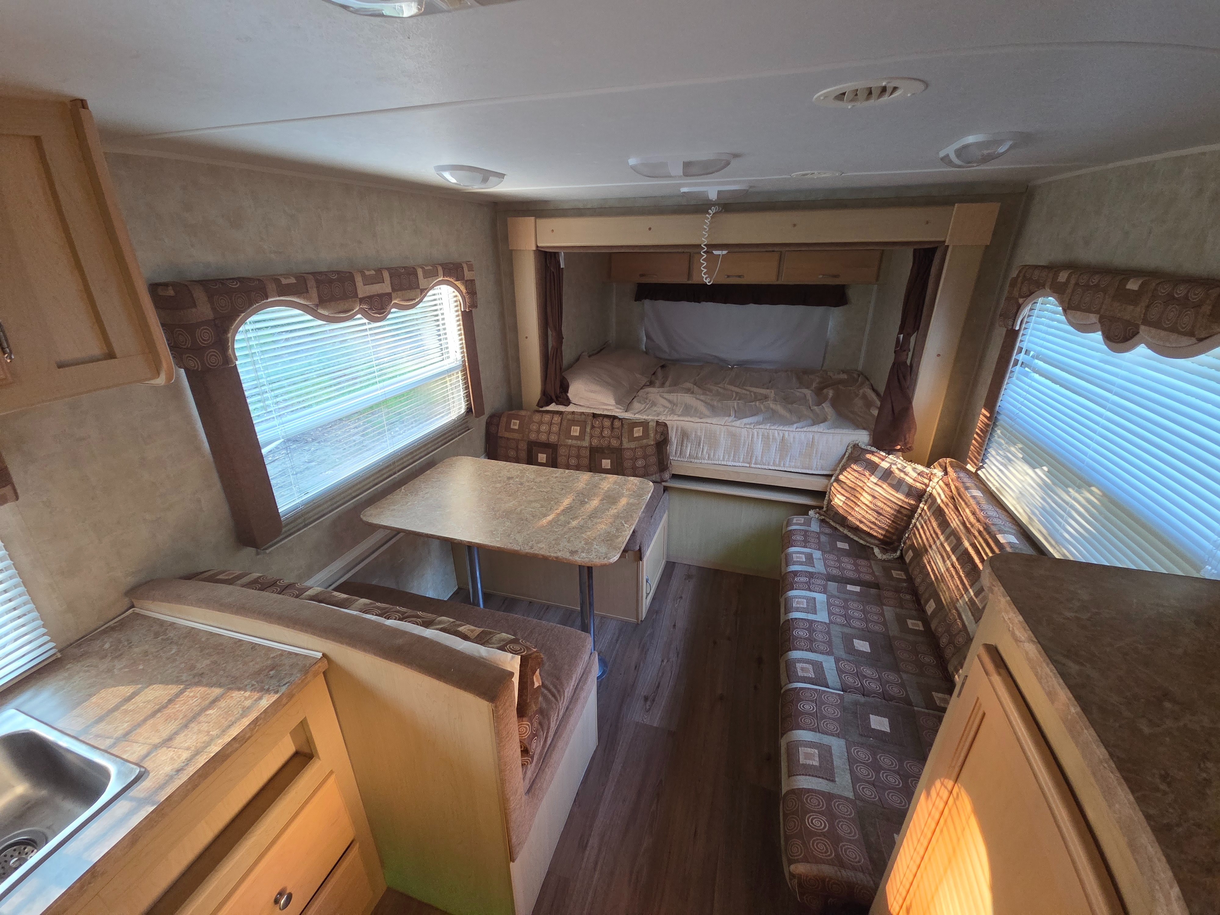 Inside an rv rental: compact living space with a bed, dining table, benches, and a small kitchen sink.. Aerolite Aerolite Trailer 2007