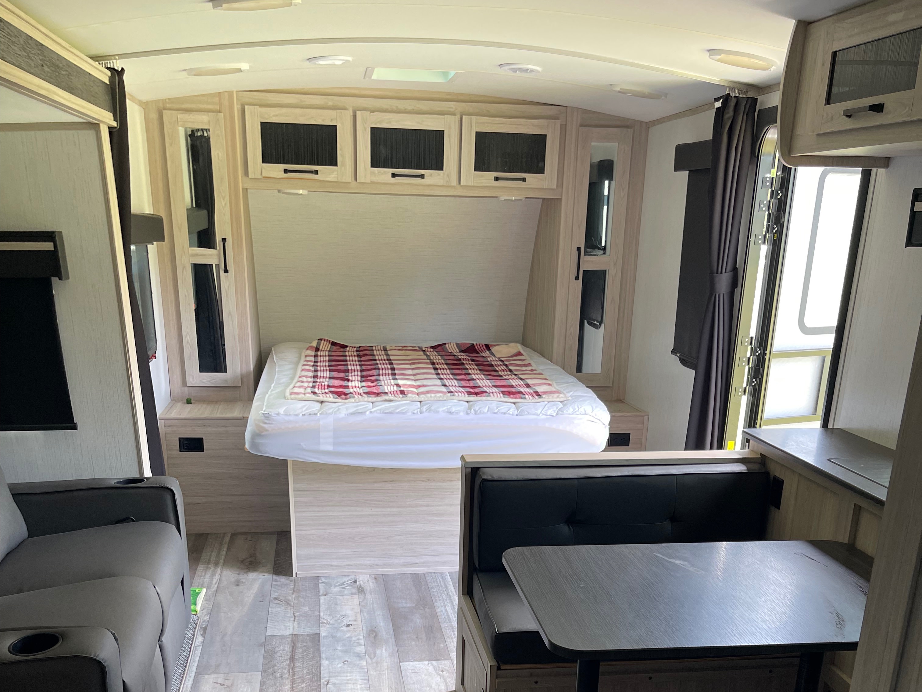 RV rental interior: cozy bedroom, dinette, and recliner in a light wood-themed space, perfect for travel.. Heartland RVs Sundance Ultra Lite 2022