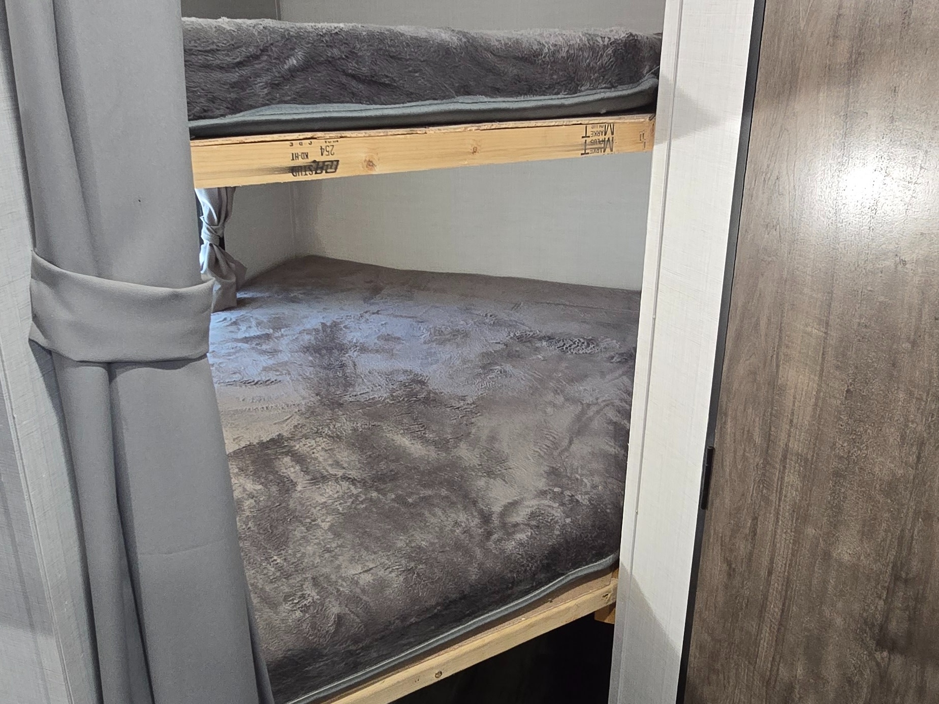 RV rental bunk beds with soft gray bedding and wooden frames, offering a cozy sleeping space for travel.. Gulf Stream Ameri-Lite 2024