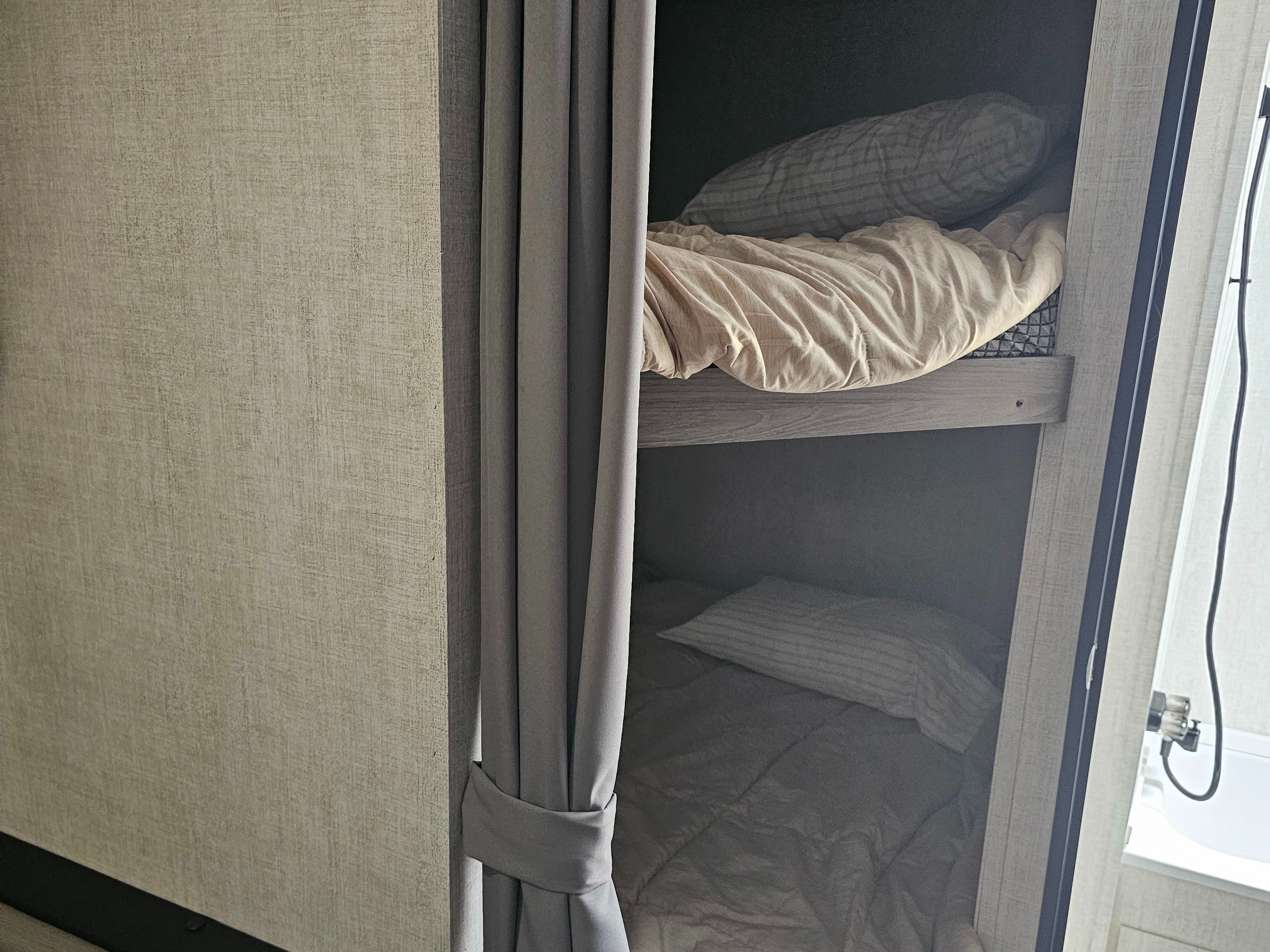 RV rental bunk beds, complete with a privacy curtain & TV backer location. A peek into the compact bathroom is on the right.. Gulf Stream Ameri-Lite 2022